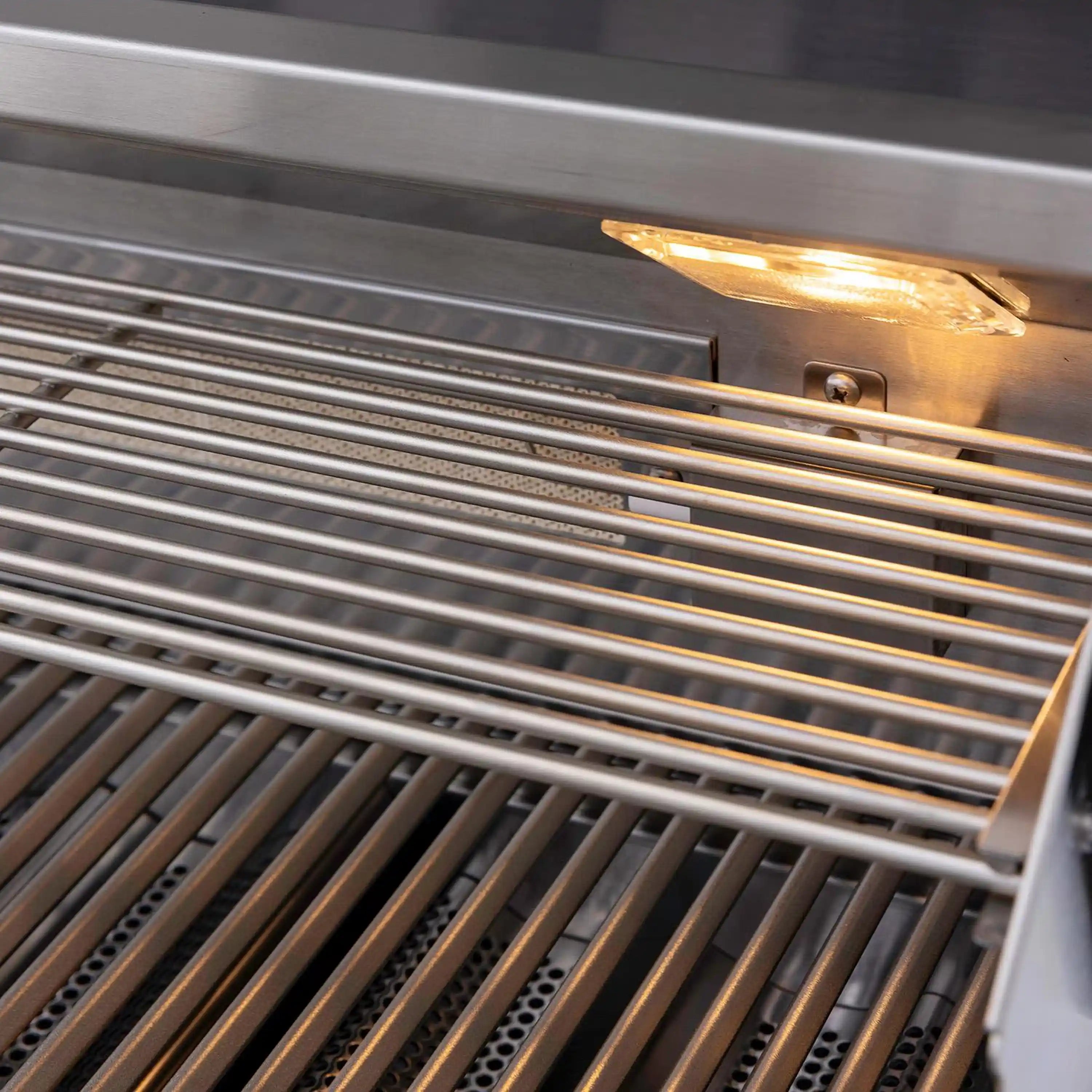 Close-up of stainless grill grates with glowing burner element above