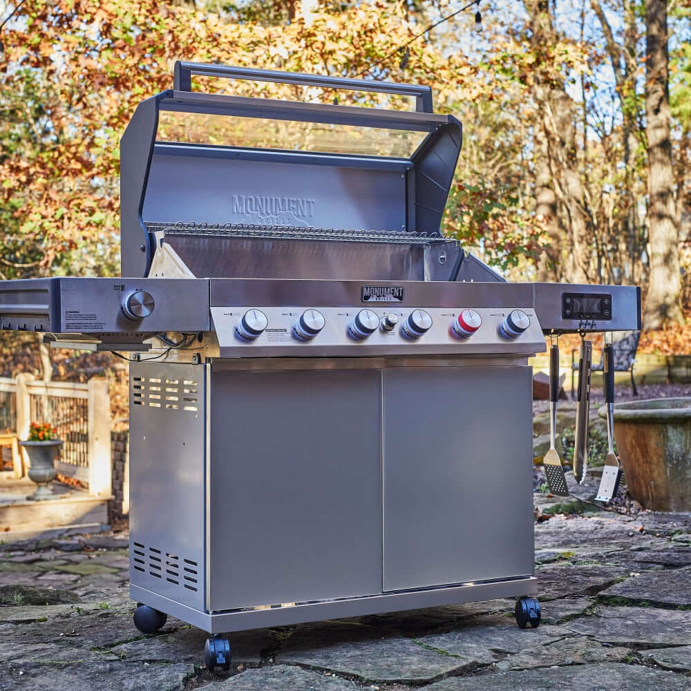 Stainless steel gas grill with open hood and control panel with multiple knobs