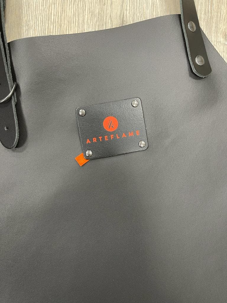Black leather grill apron with centered logo plate and metal rivets