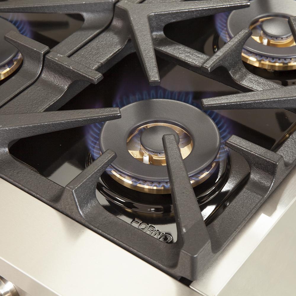 Close-up of gas range burner head with black grate and brass flame ring