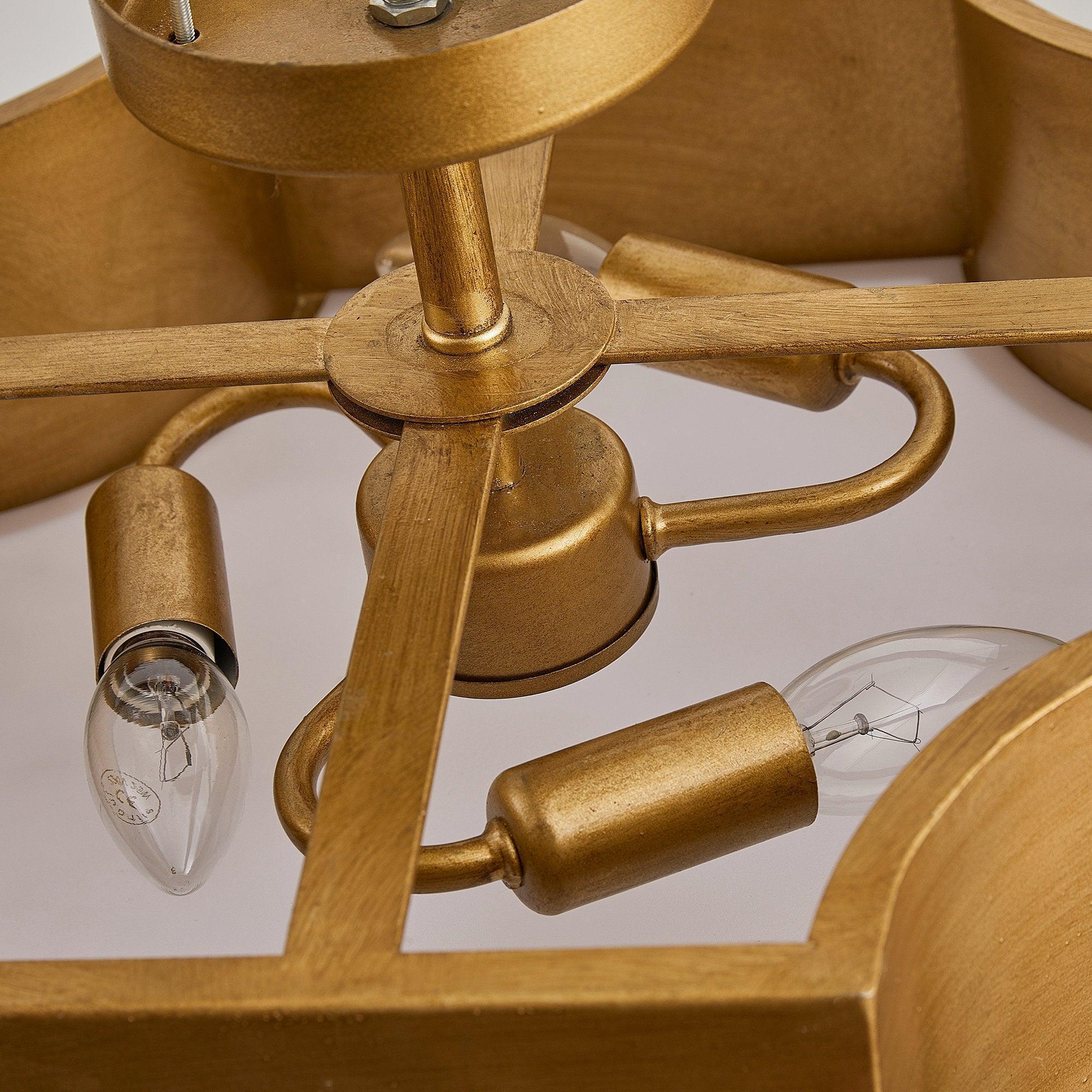 Brushed gold semi-flush light showing metal arms and glass bulb sockets