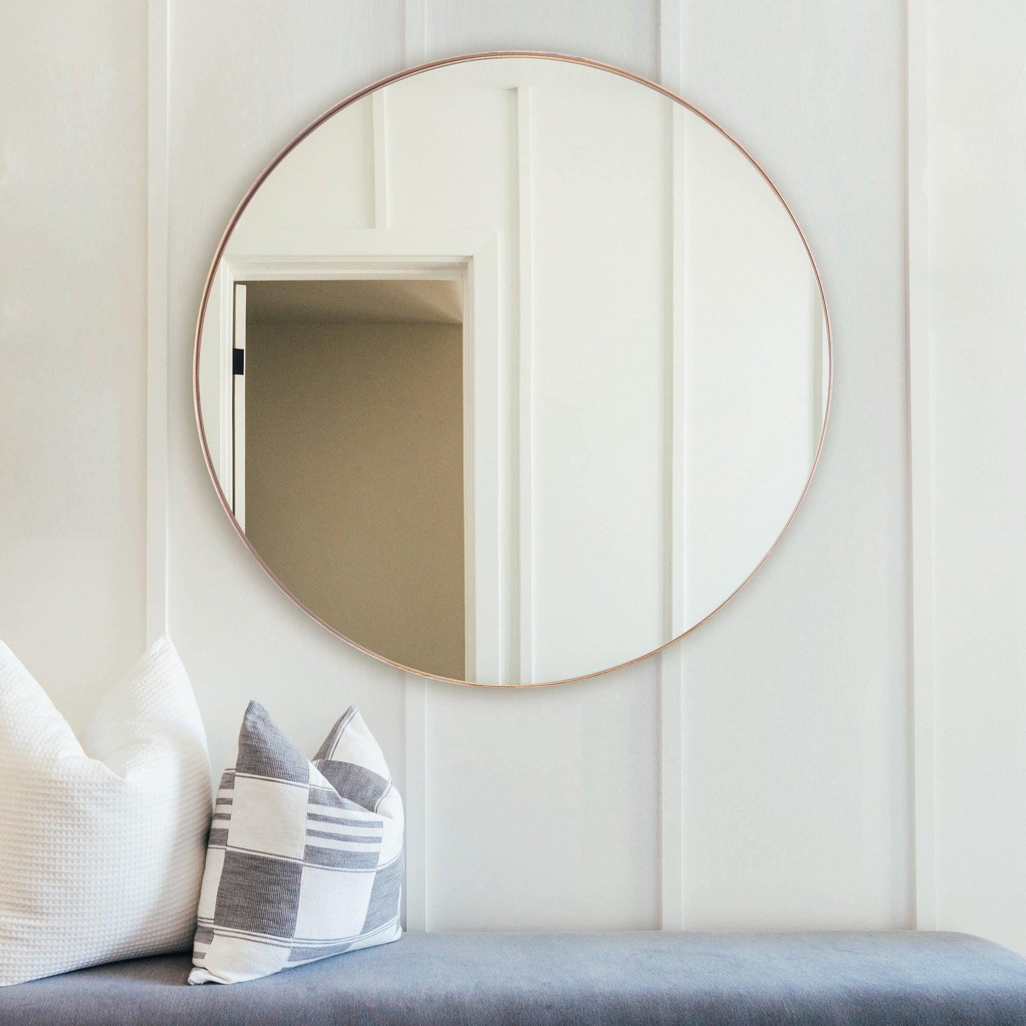 Round wall mirror with thin golden frame reflecting vertical stripes.