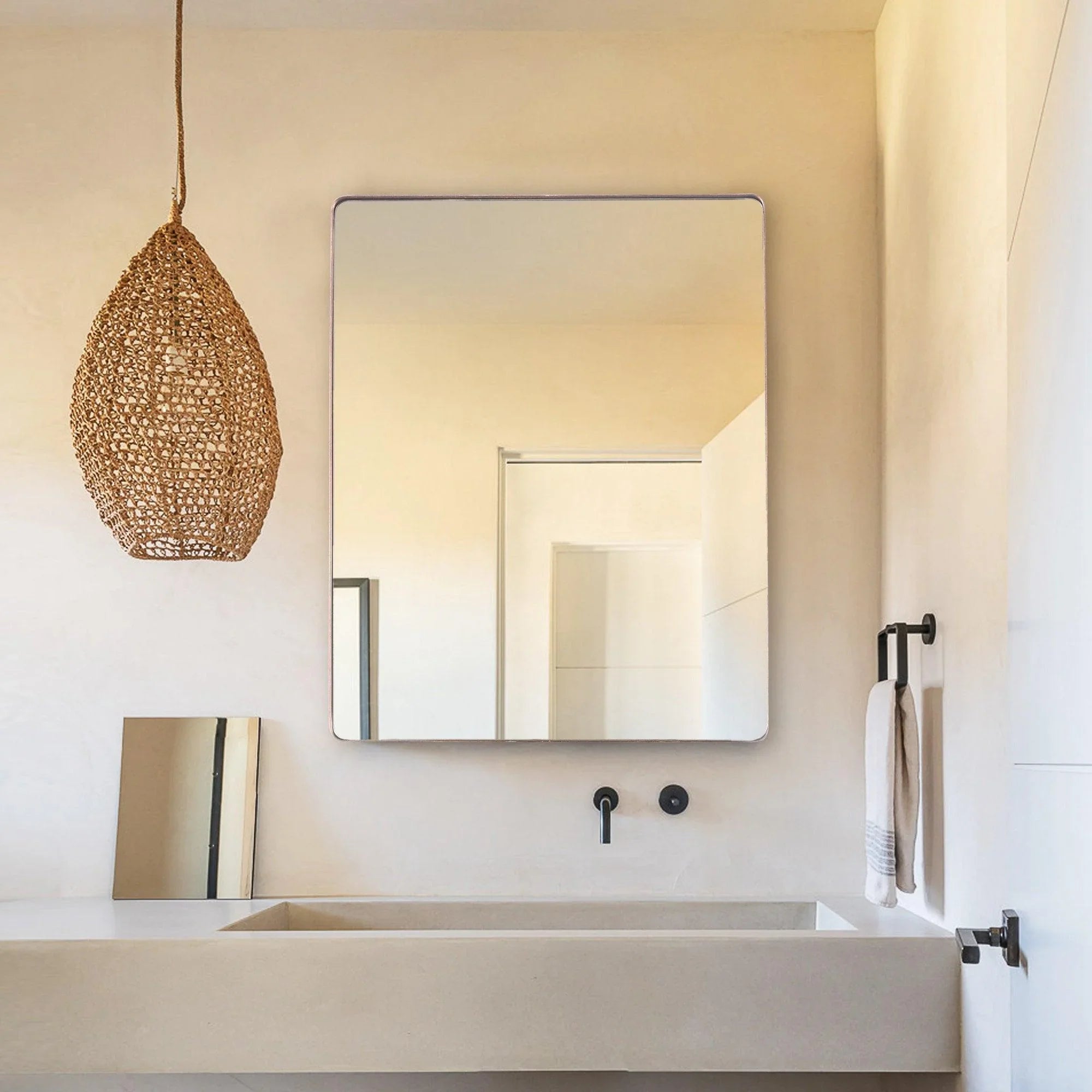 Square wall mirror with gold-toned frame mounted on wall, rounded corners