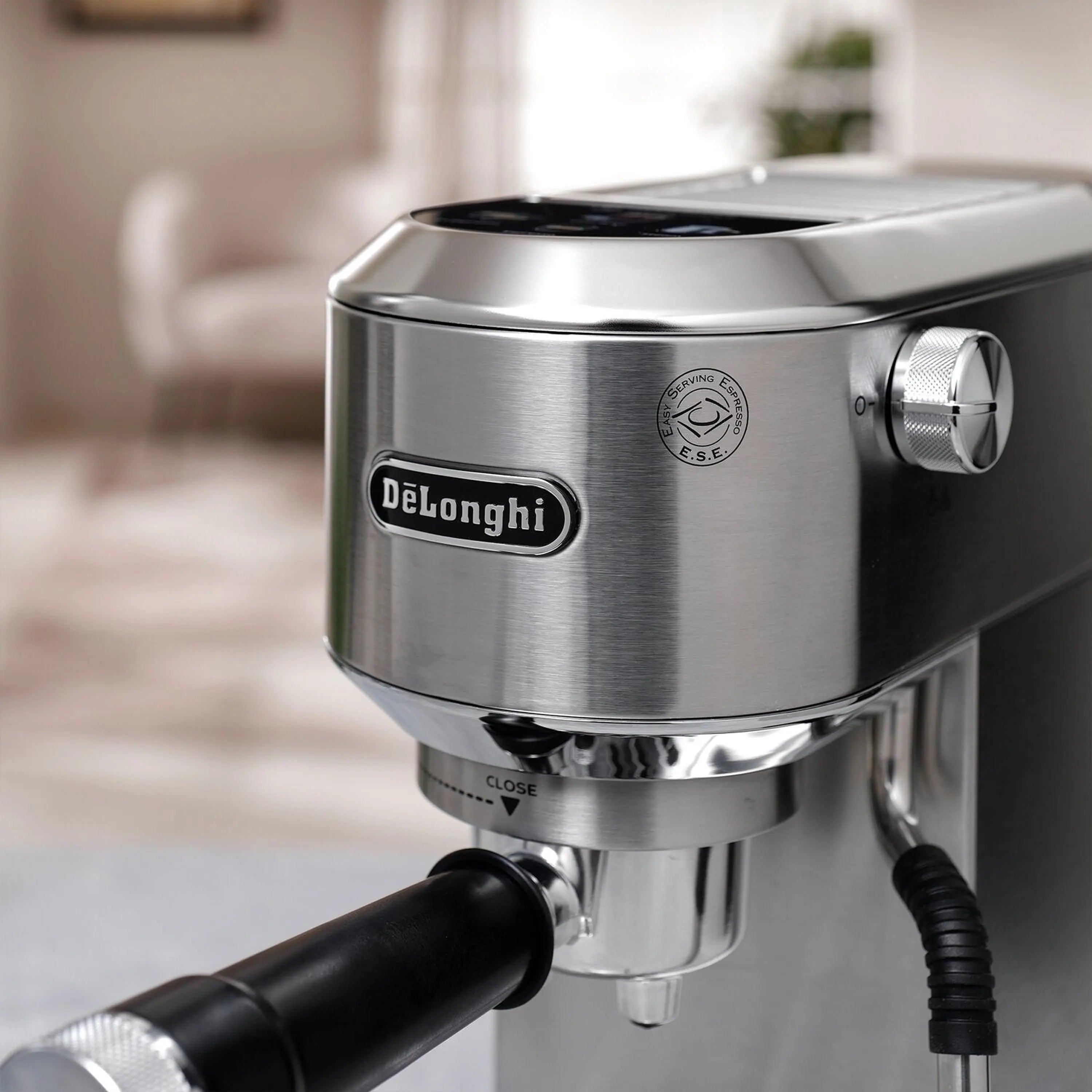 Stainless espresso machine front view with frothing wand and coffee spout