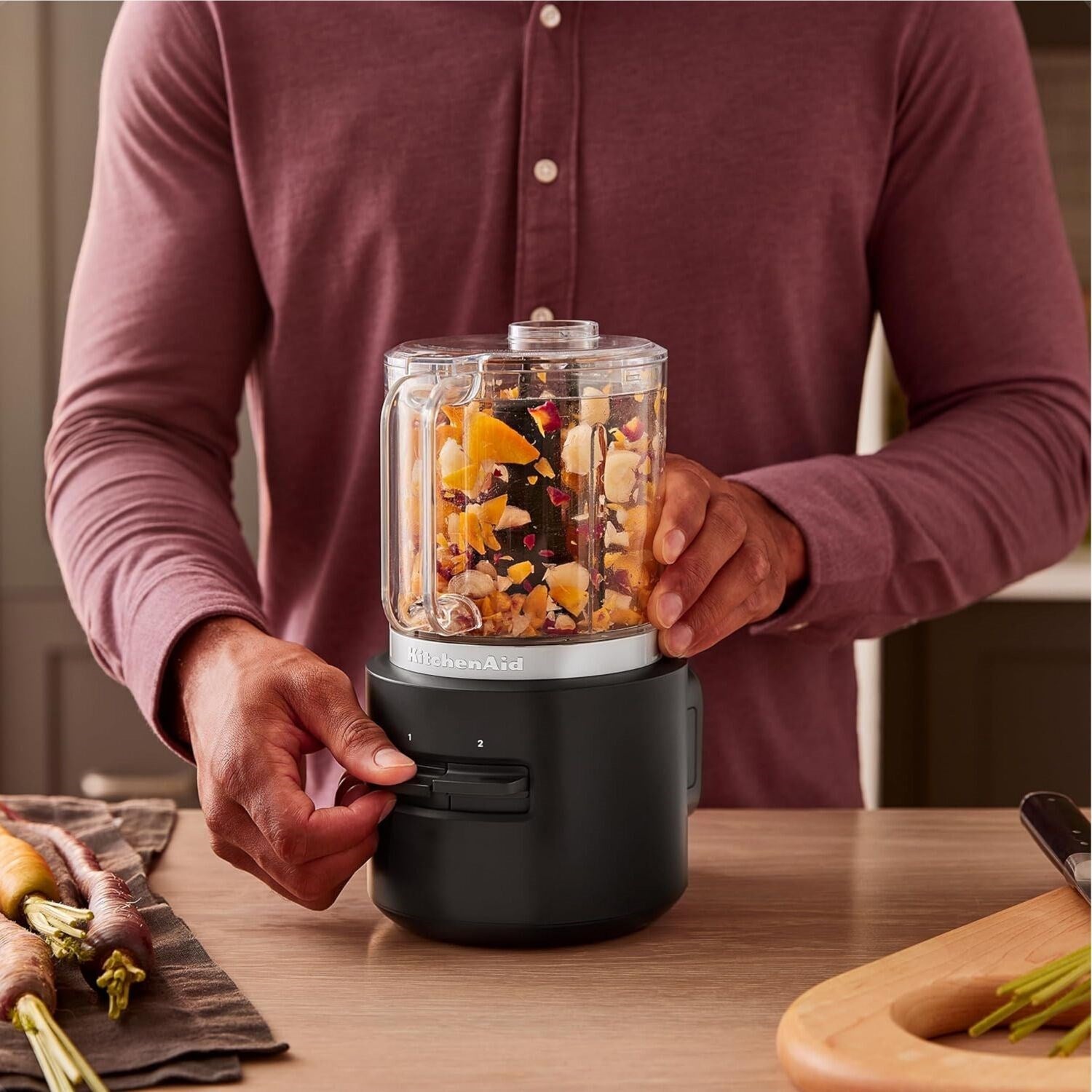 Person holding a clear-cup black cordless chopper filled with chopped ingredients
