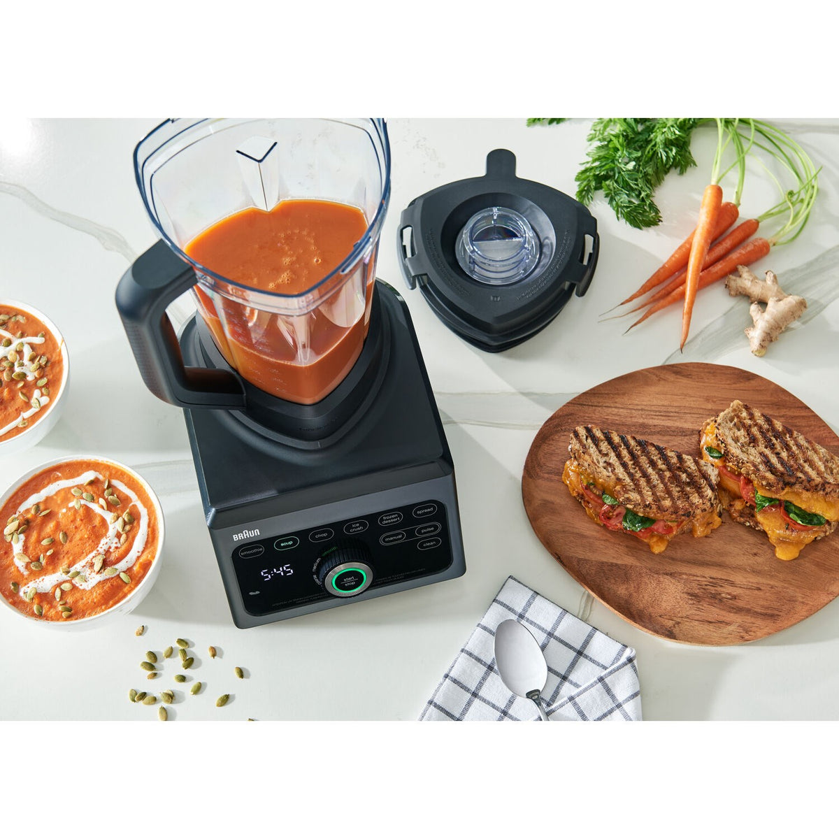 Black blender with clear jar holding orange smoothie on countertop