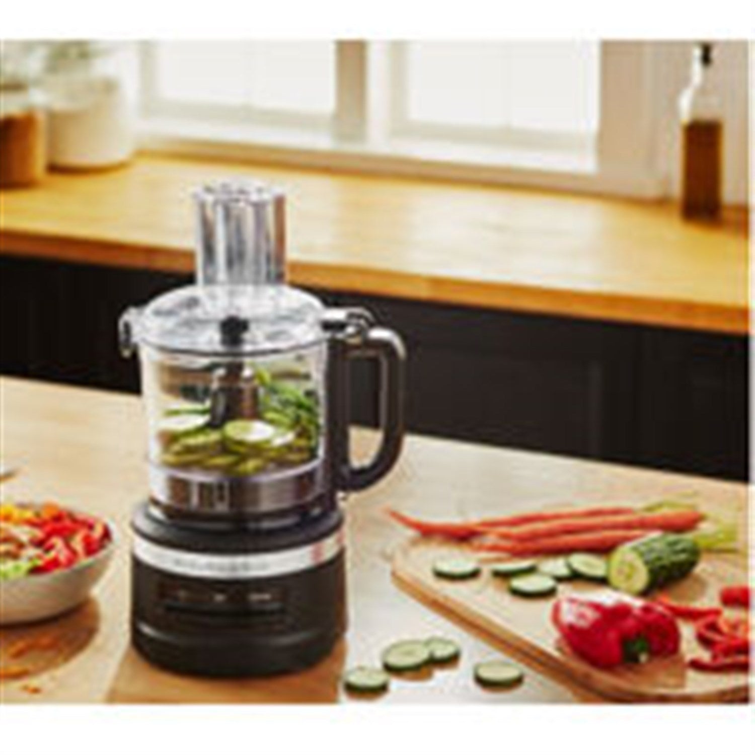 White food processor on countertop with clear bowl and visible sliced ingredients