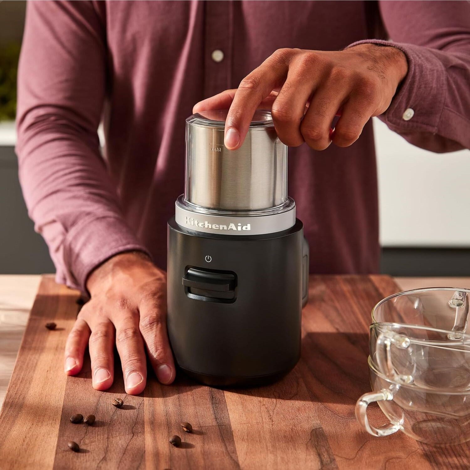 Black matte cordless coffee grinder on countertop with clear bean grinding top