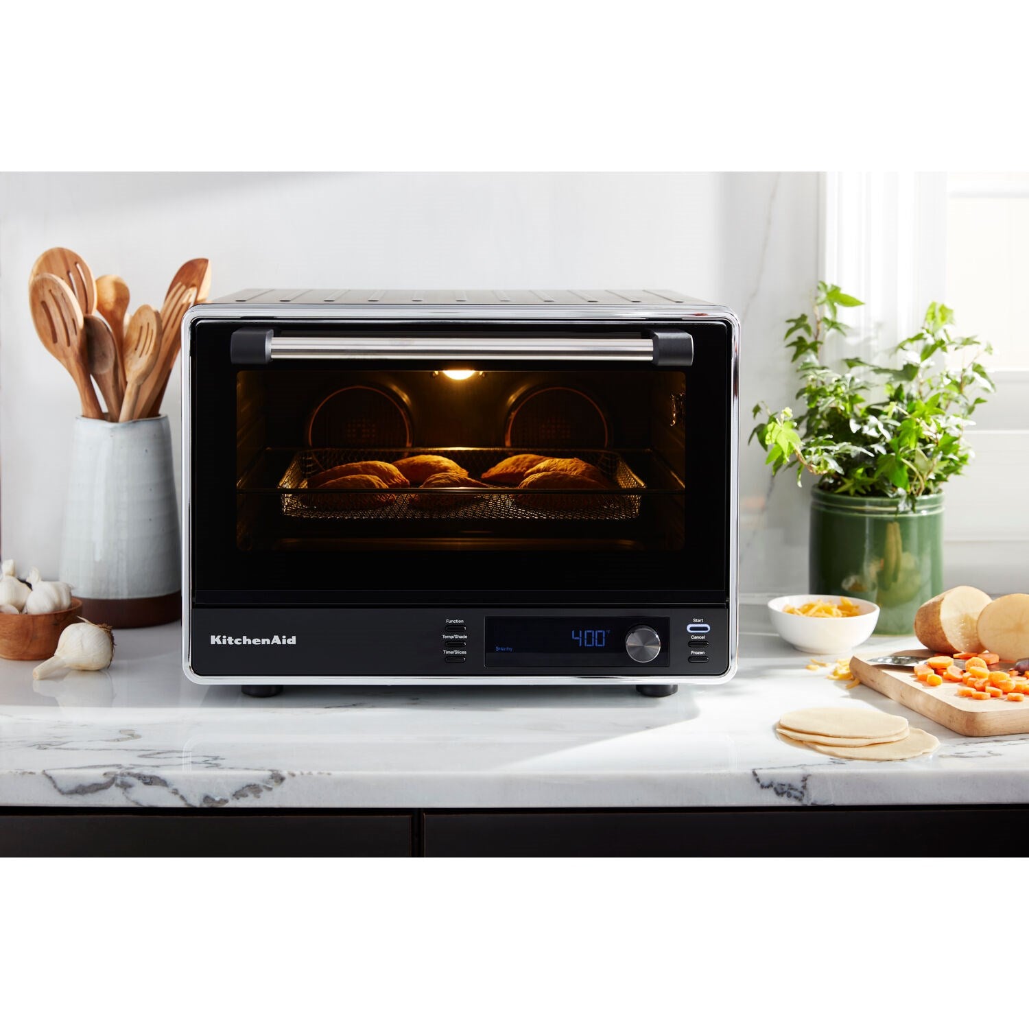 Black countertop convection oven with interior light on and food baking inside
