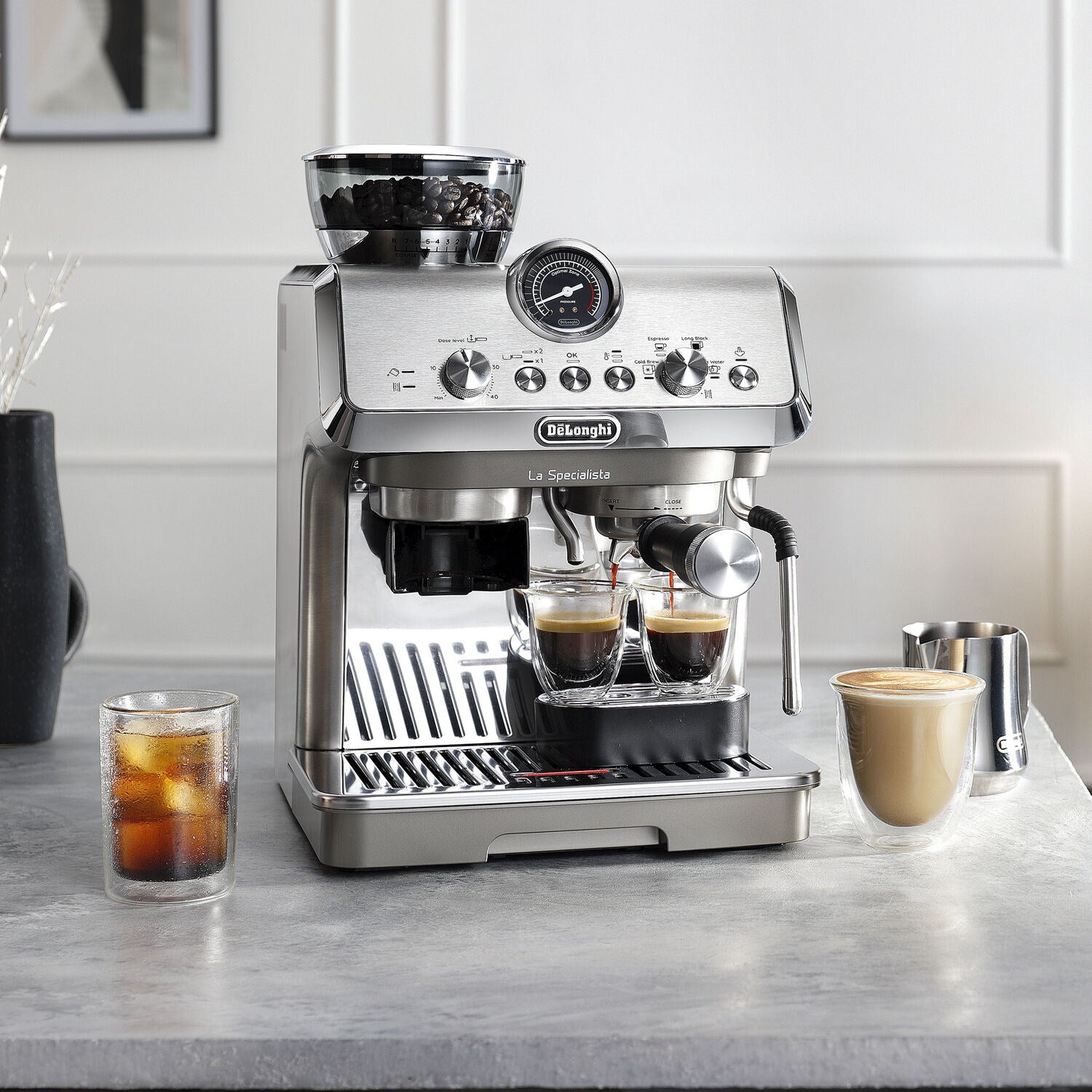 Silver espresso machine on countertop with two filled cups and milk cup