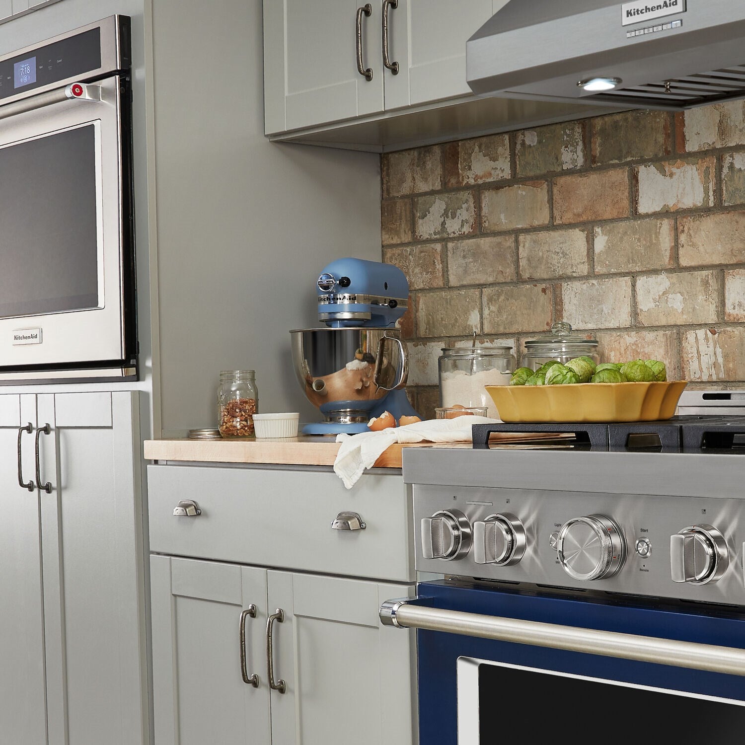 Blue tilt-head stand mixer on a kitchen counter with attachments in view