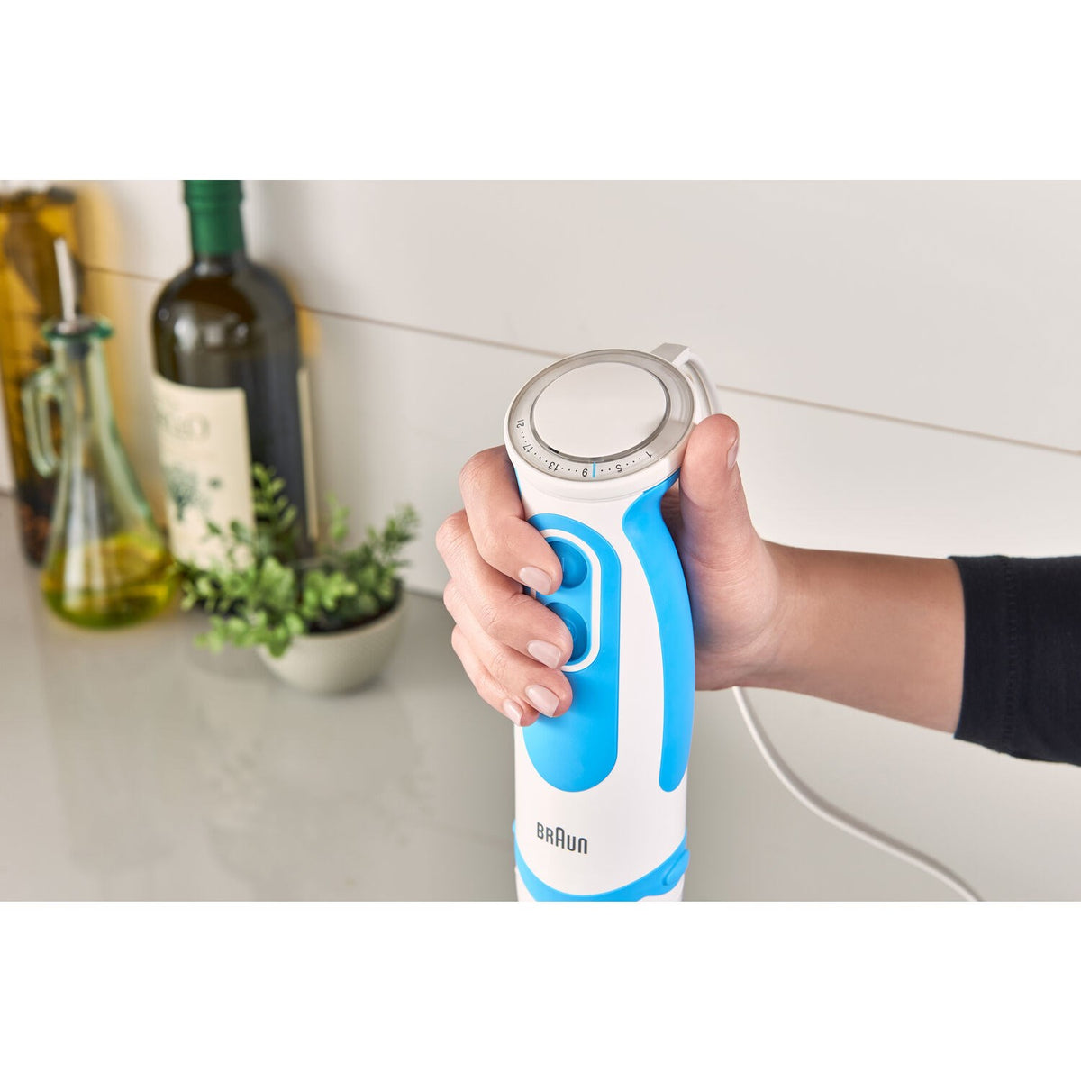 Blue and white handheld blender with grip held in a hand
