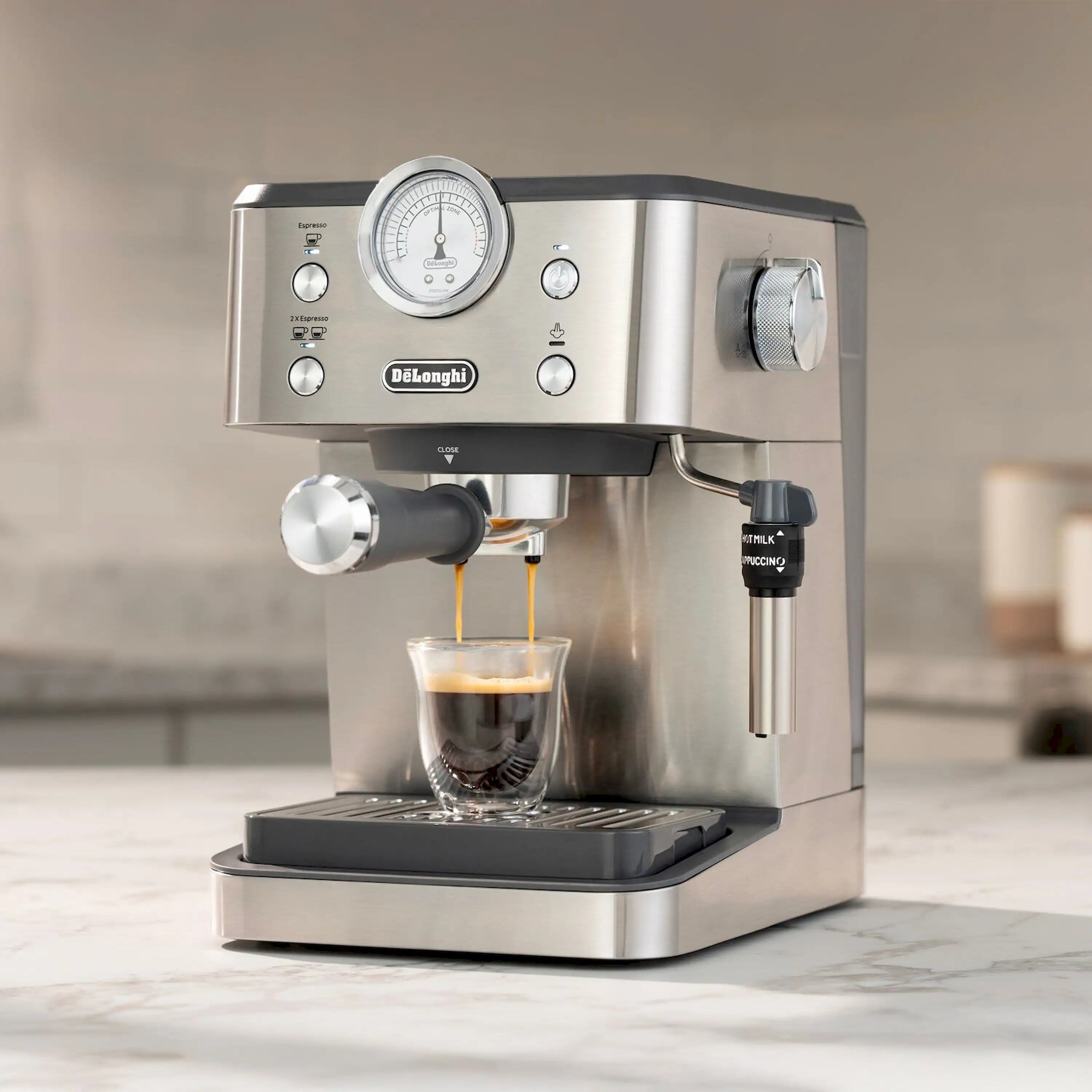 Front view of stainless espresso machine dispensing espresso into drip tray