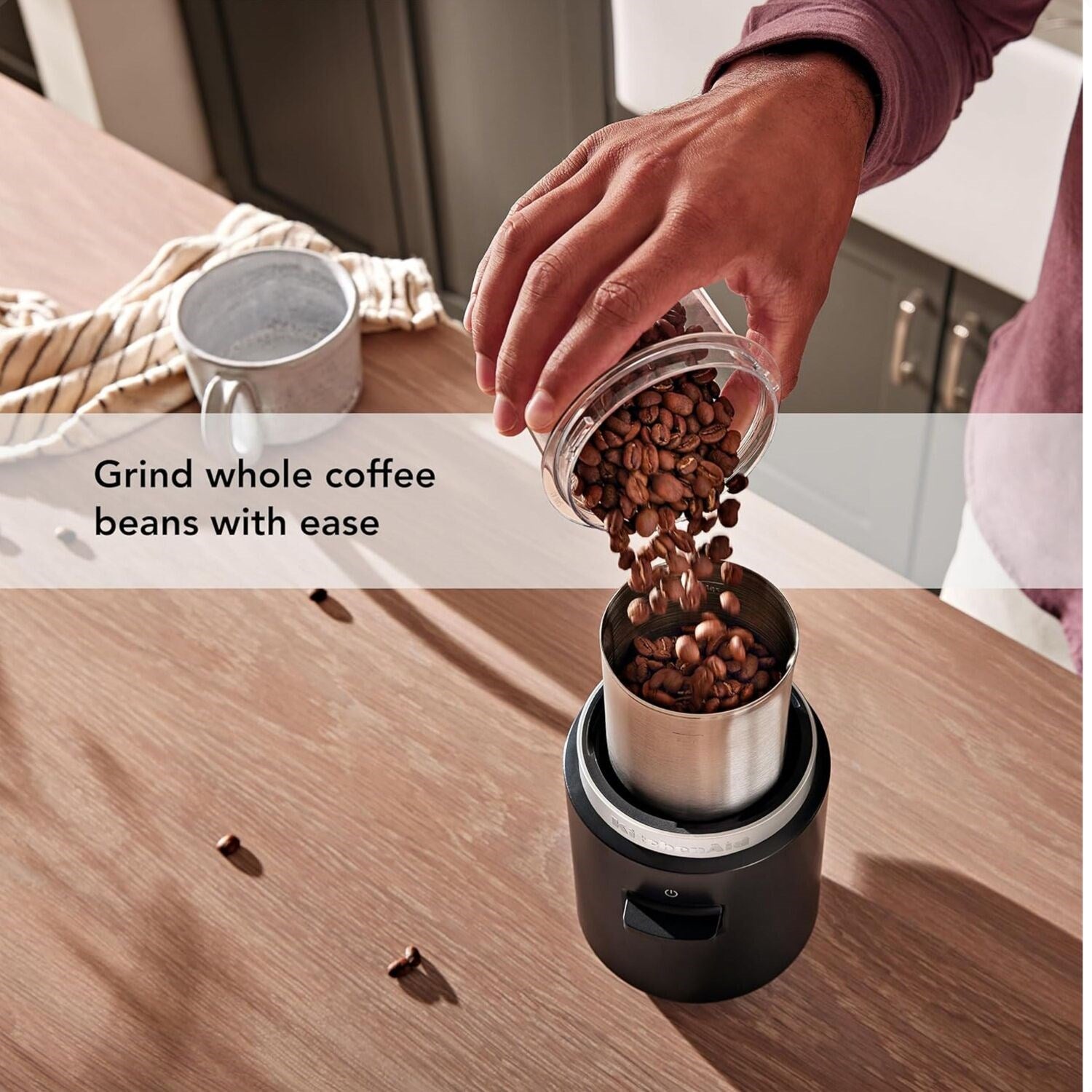 Black matte cordless blade coffee grinder with clear top container pouring coffee beans