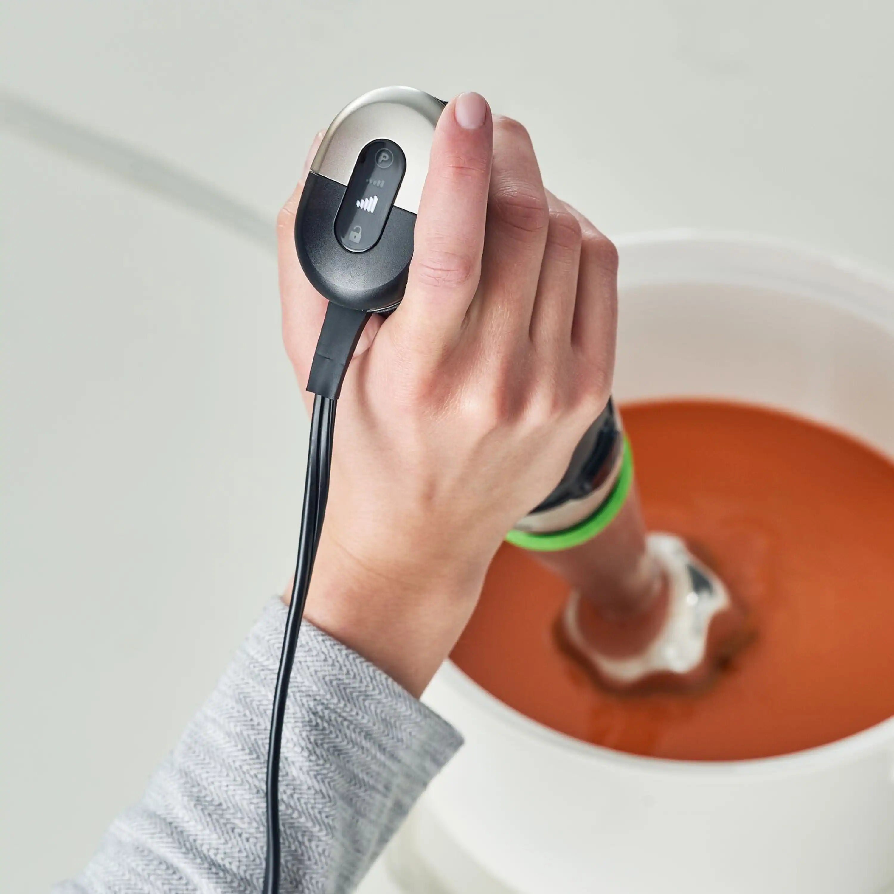 Hand holding Braun SmartSpeed hand blender over a bowl, black-and-silver body