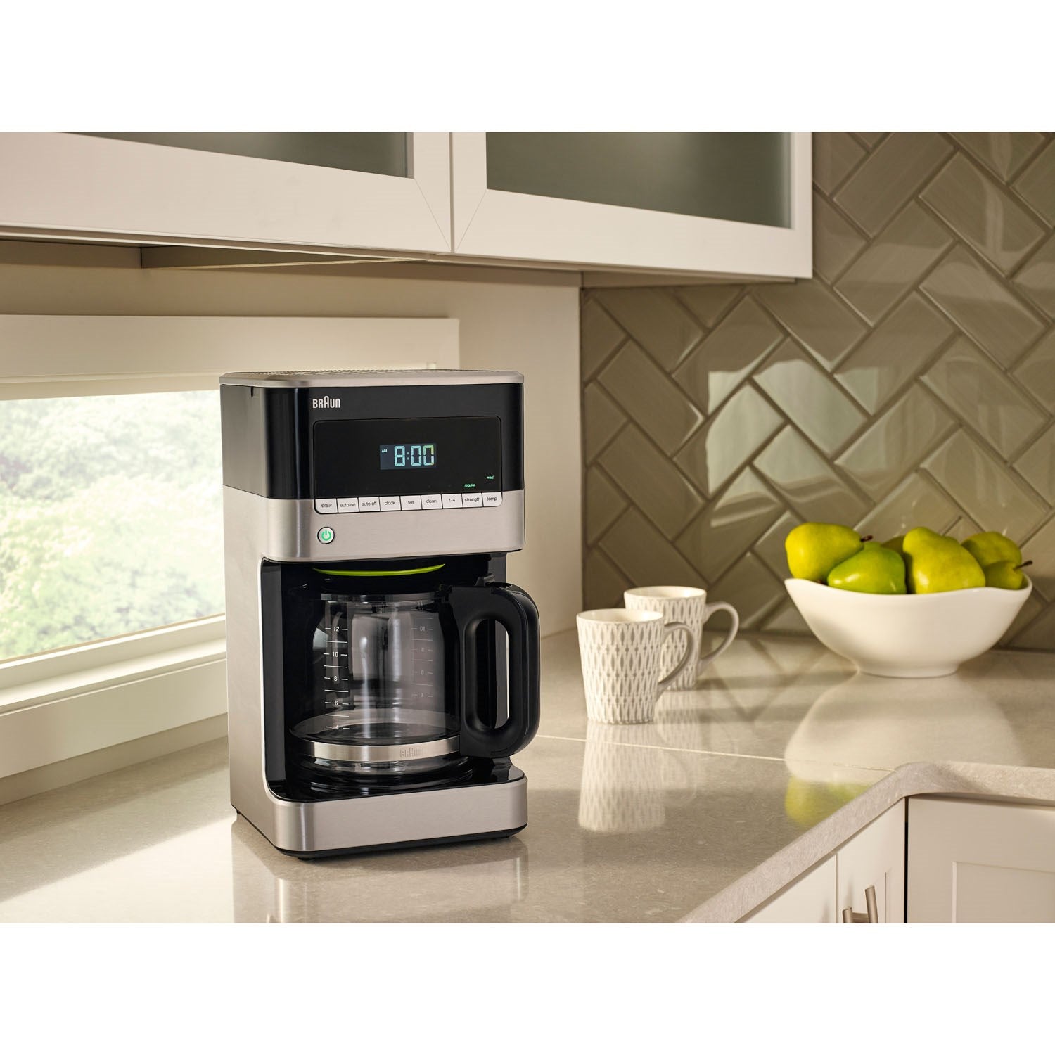 Black and stainless steel drip coffee maker on countertop with coffee mug and carafe