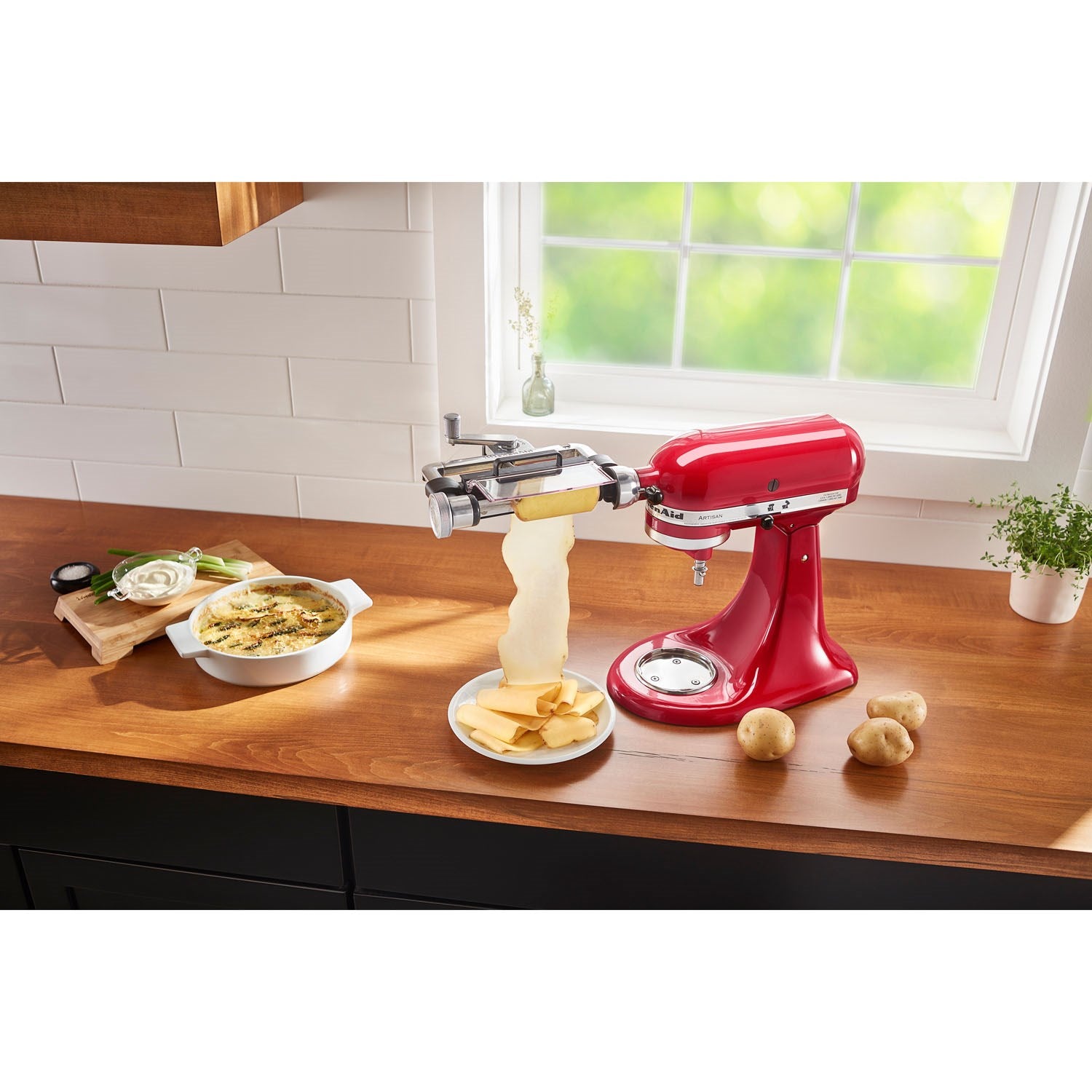 Vegetable sheet cutter attachment on red stand mixer with stacked vegetable sheets