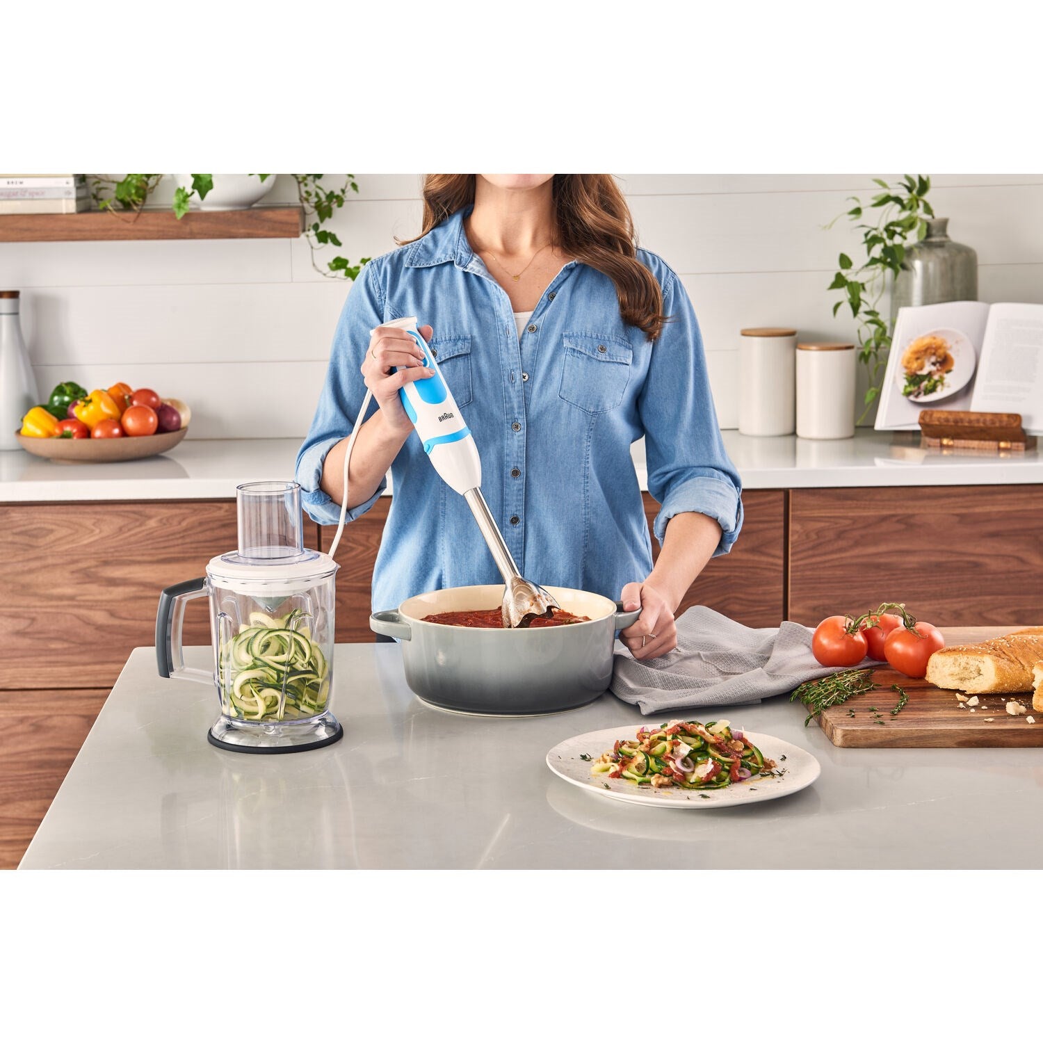 Hand blender in use above mixing bowl with blade and blending beaker