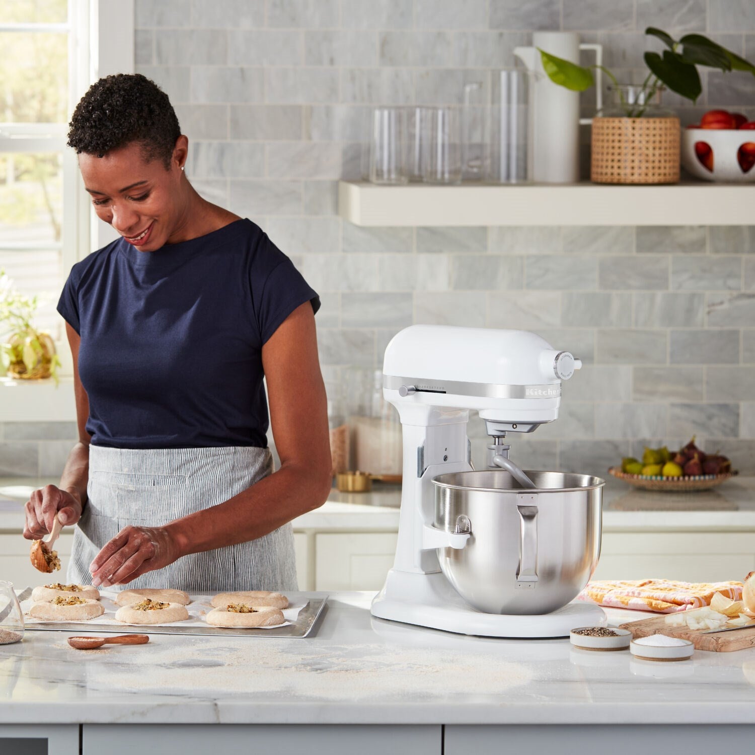 White KitchenAid stand mixer with stainless bowl, shown in use on a kitchen counter