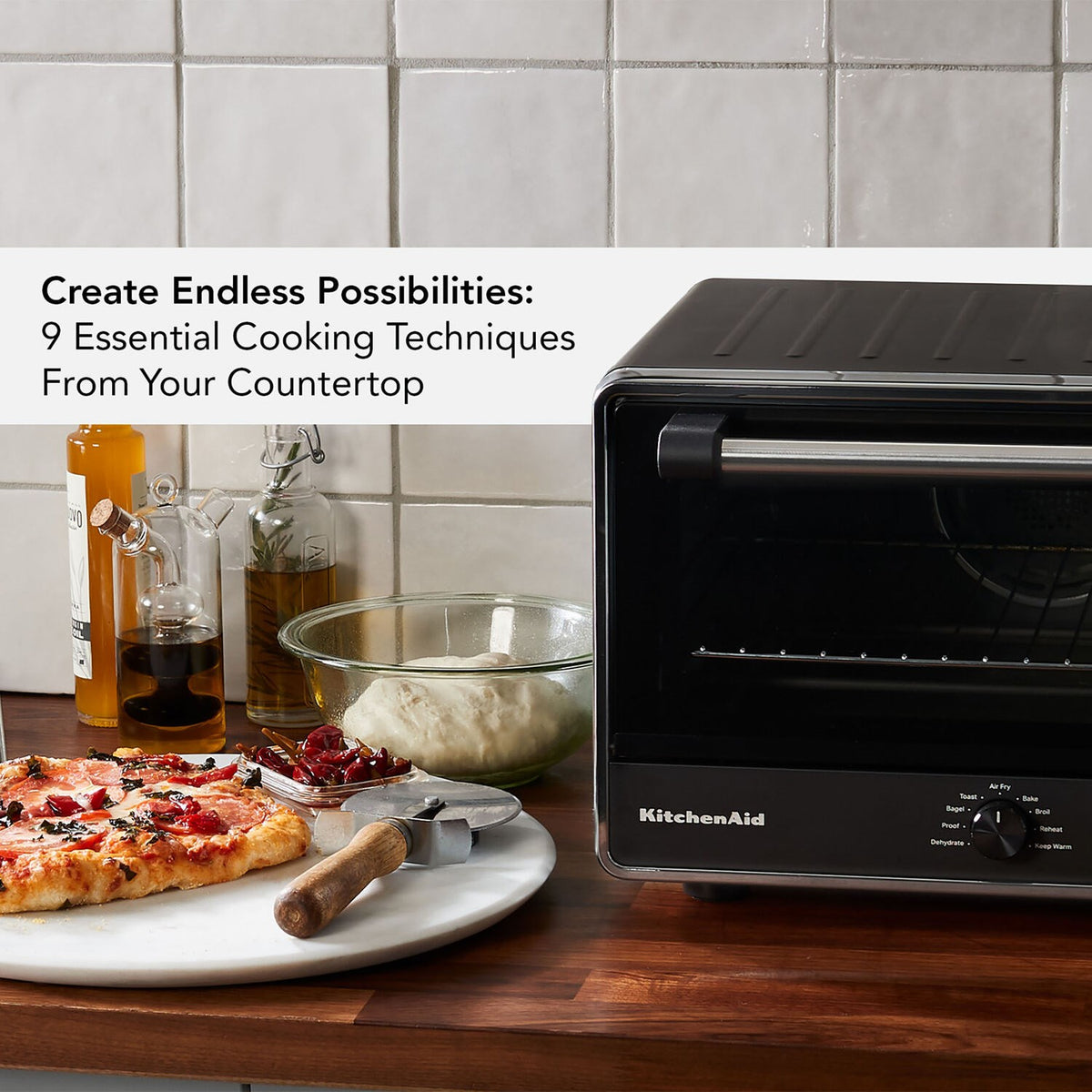 KitchenAid black countertop oven with open door and interior rack, on a kitchen counter