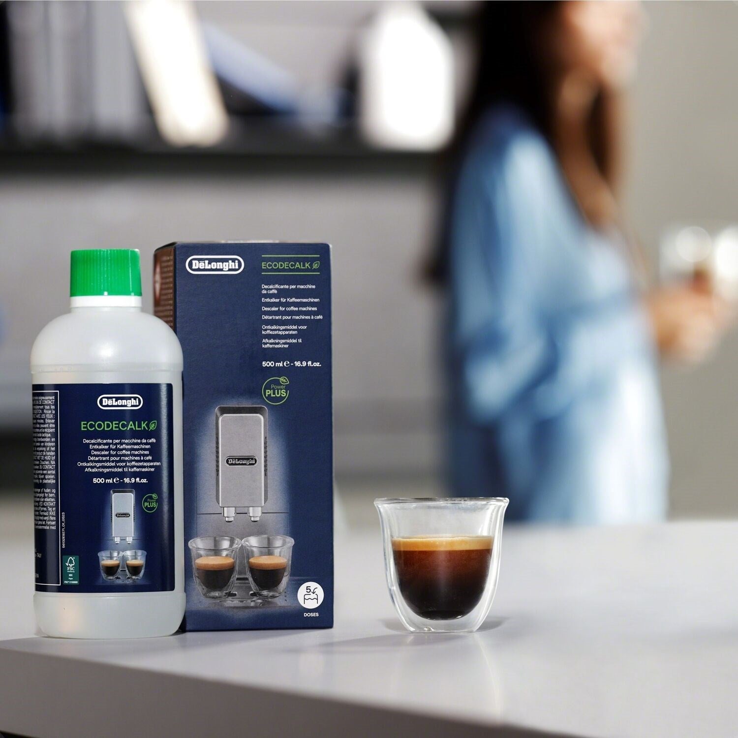 De'Longhi EcoDecalk bottle with green cap and product box, with a cup of coffee.