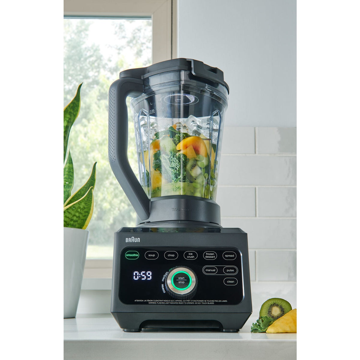 Black countertop blender with clear jar holding chopped vegetables