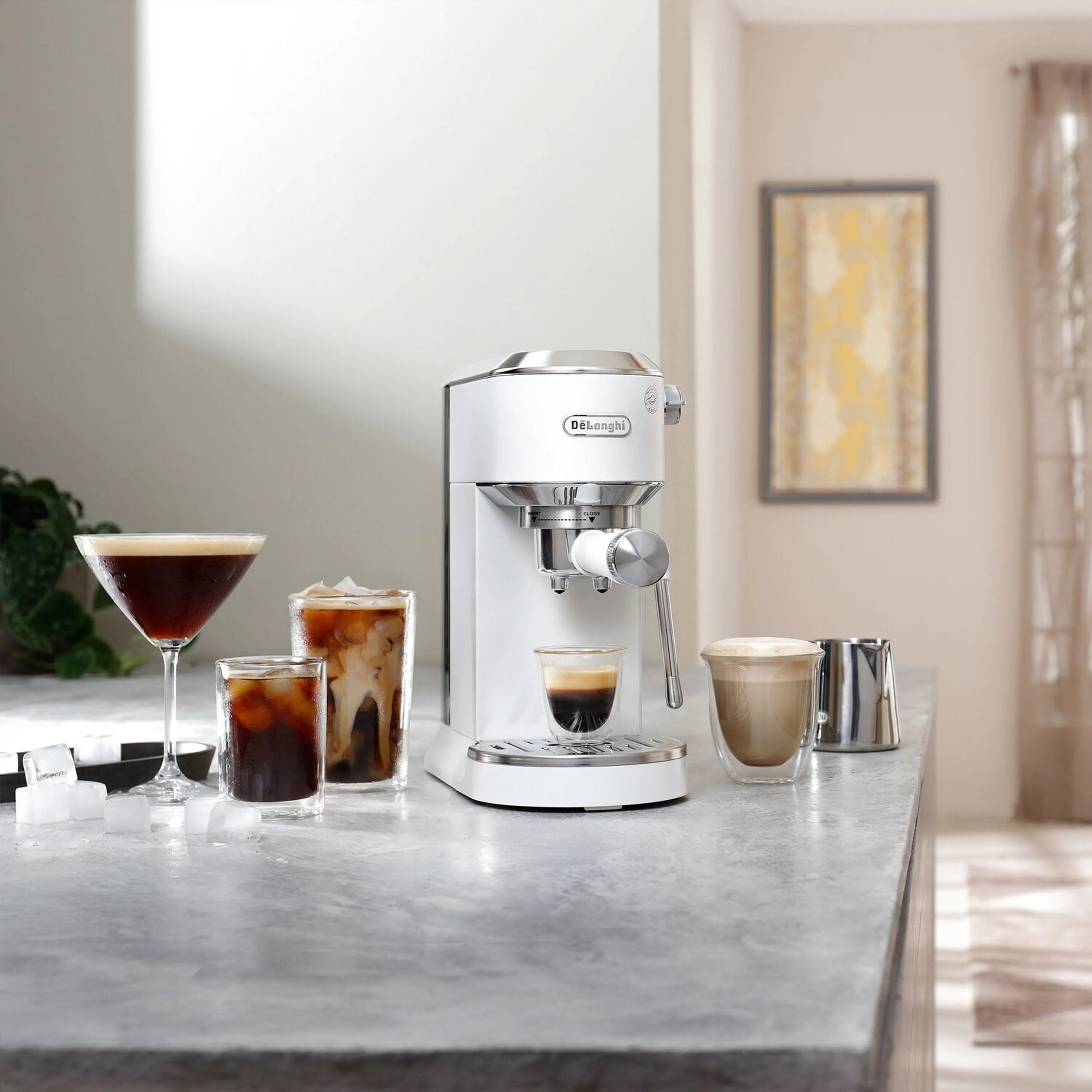 Espresso machine on kitchen counter with hot and iced coffee cups and a frothing wand