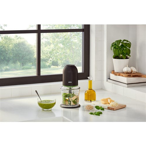 Black mini food chopper on kitchen counter with clear bowl and green-tinted accents