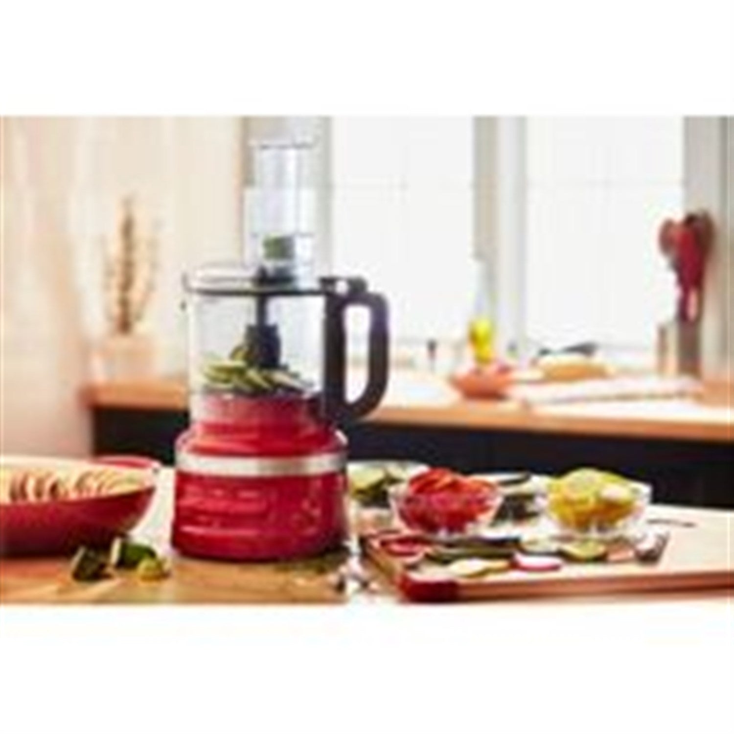 Red food processor on countertop with clear bowl and black handle