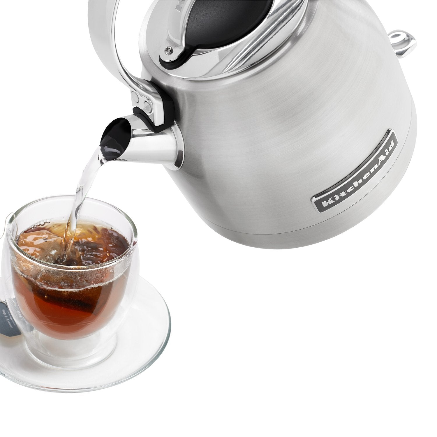 Brushed stainless electric kettle pouring from spout into a cup