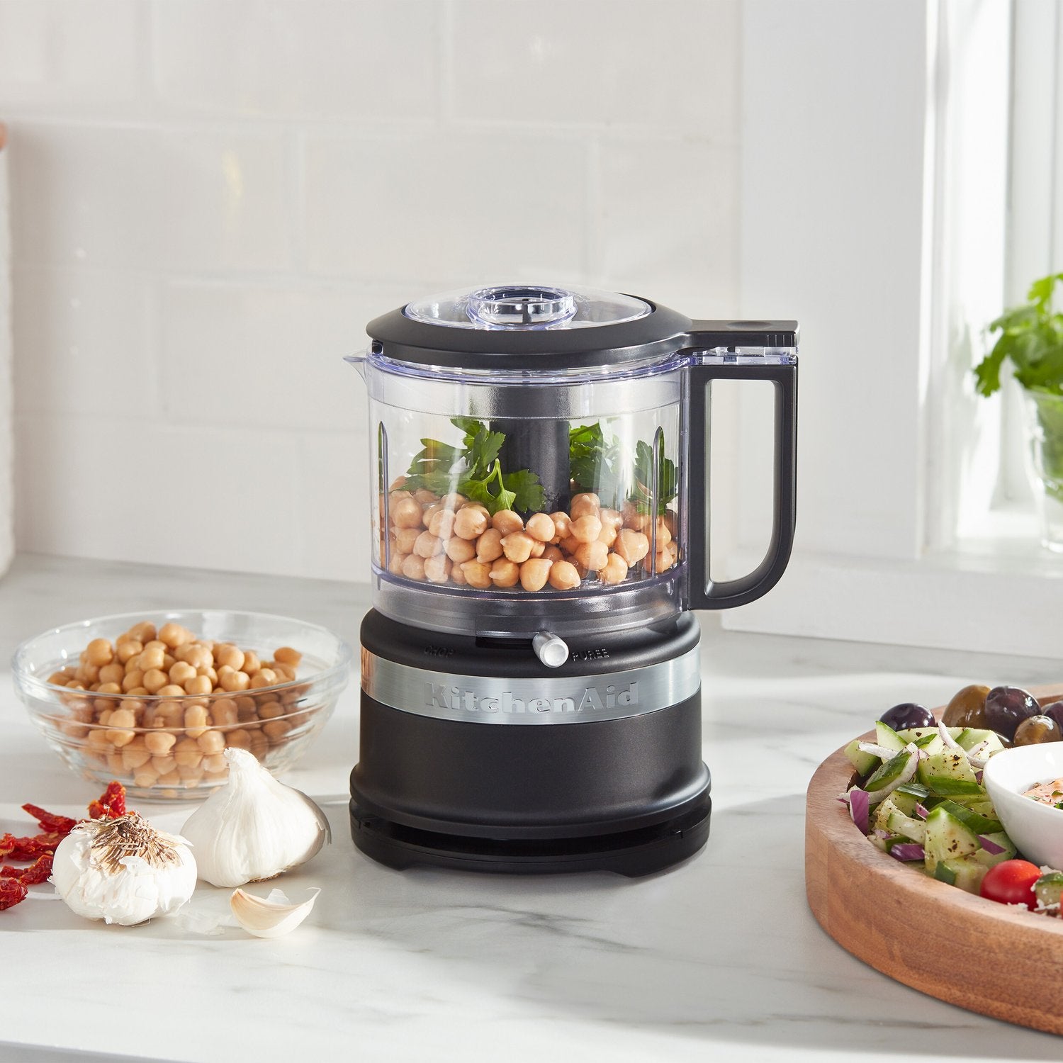Black matte food chopper with clear 3.5-cup bowl, lid, and chopping ingredients inside