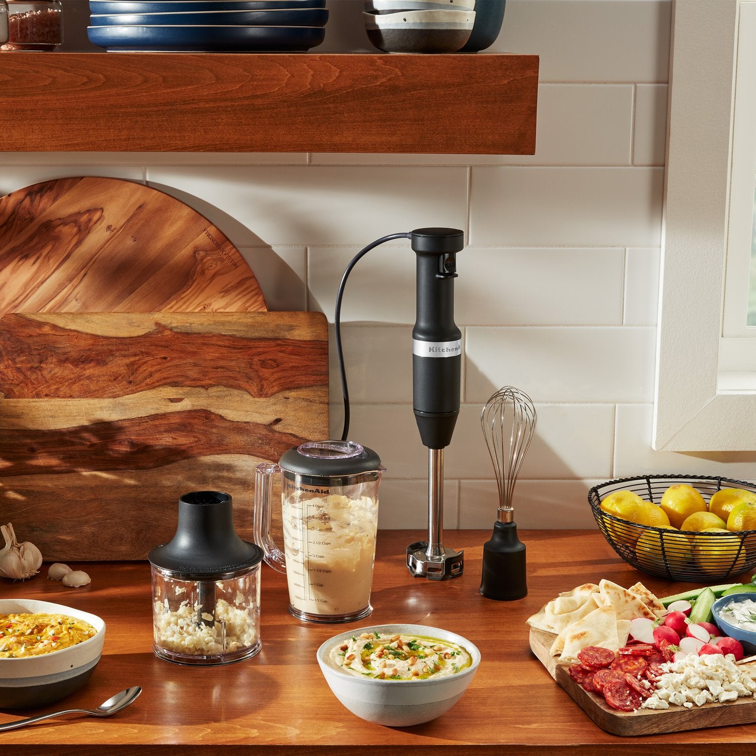 Black matte immersion blender with blending jar and whisk attachment on countertop