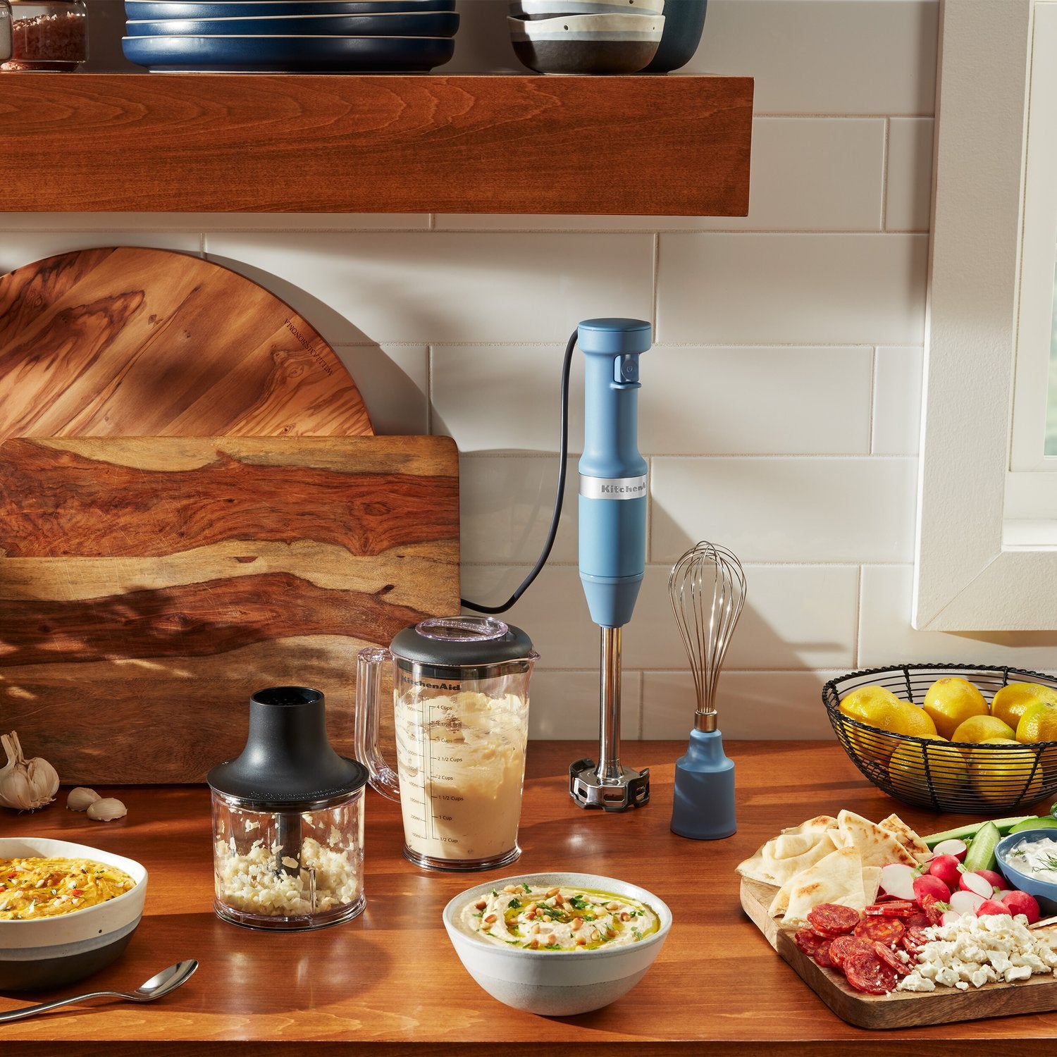 Blue corded immersion blender with blending jar and whisk attachment on counter