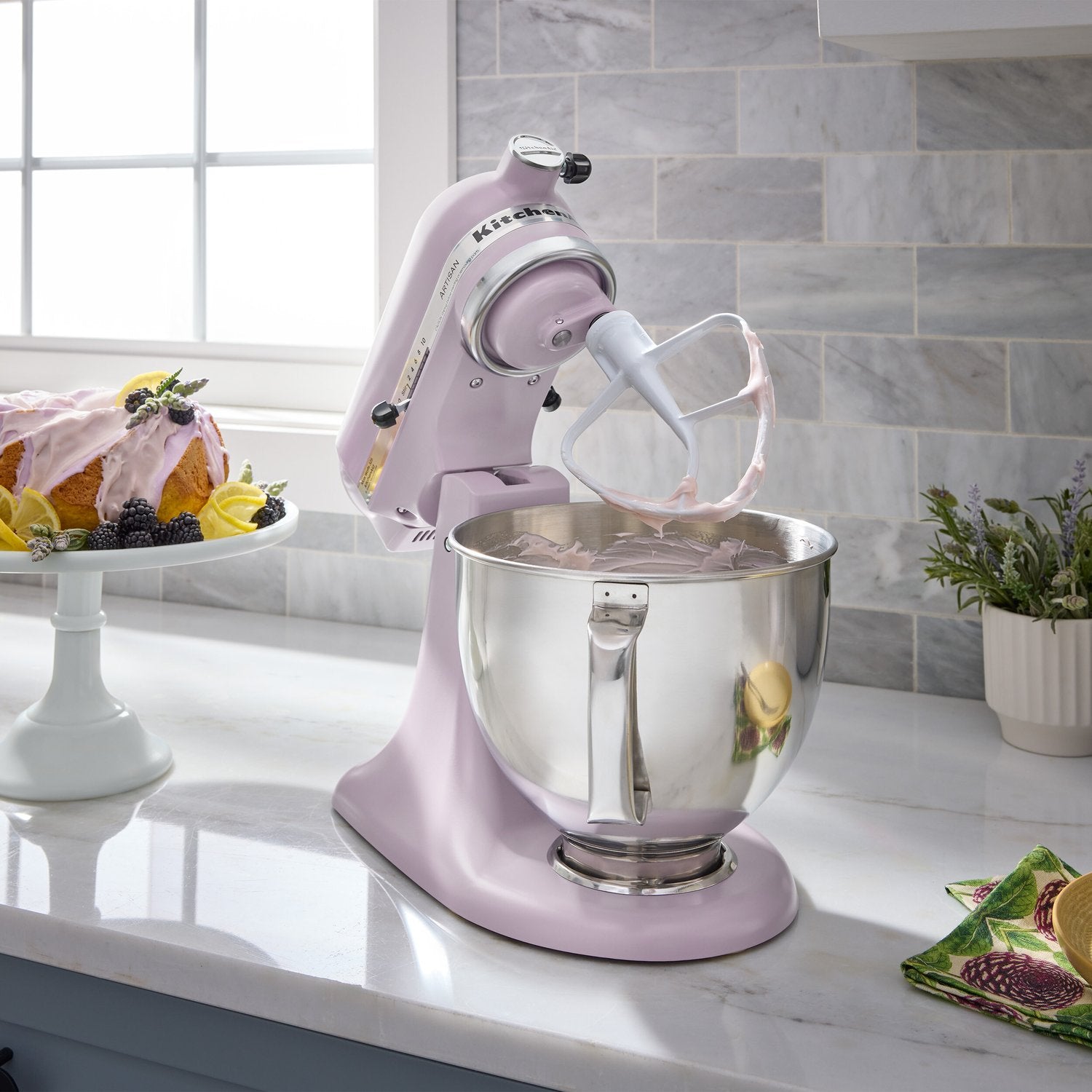 Purple tilt-head stand mixer in kitchen with stainless bowl and wire whisk attachment