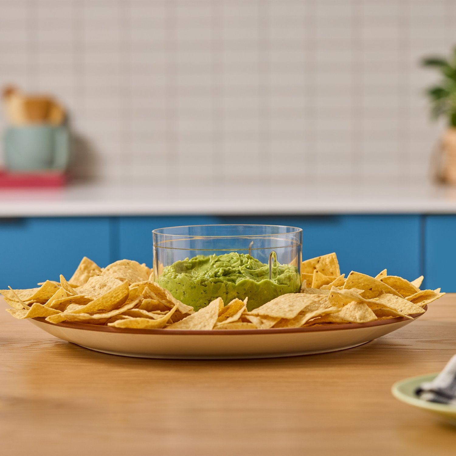 Clear chopper bowl filled with green puree and chips on a serving plate