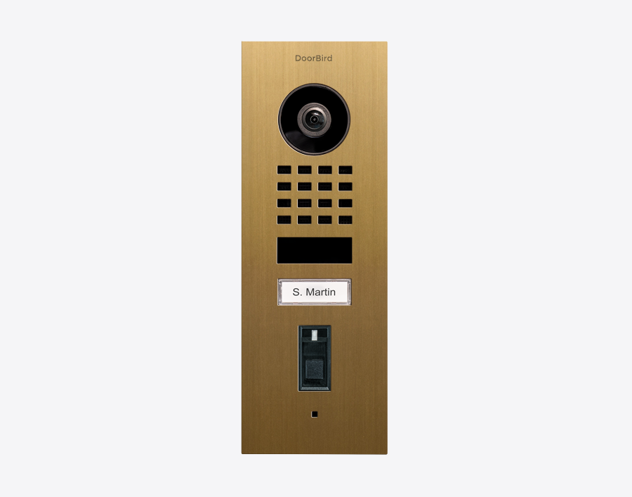 DoorBird flush-mount video door station in gold, with black camera and keypad panel