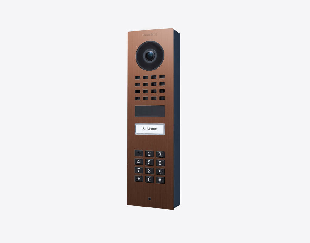 Bronze DoorBird surface-mount video door station with camera lens and keypad call buttons