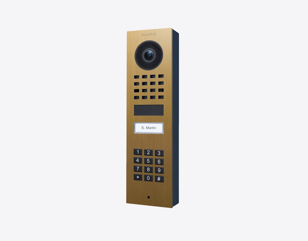 Gold and black surface-mount video door station with camera lens and keypad