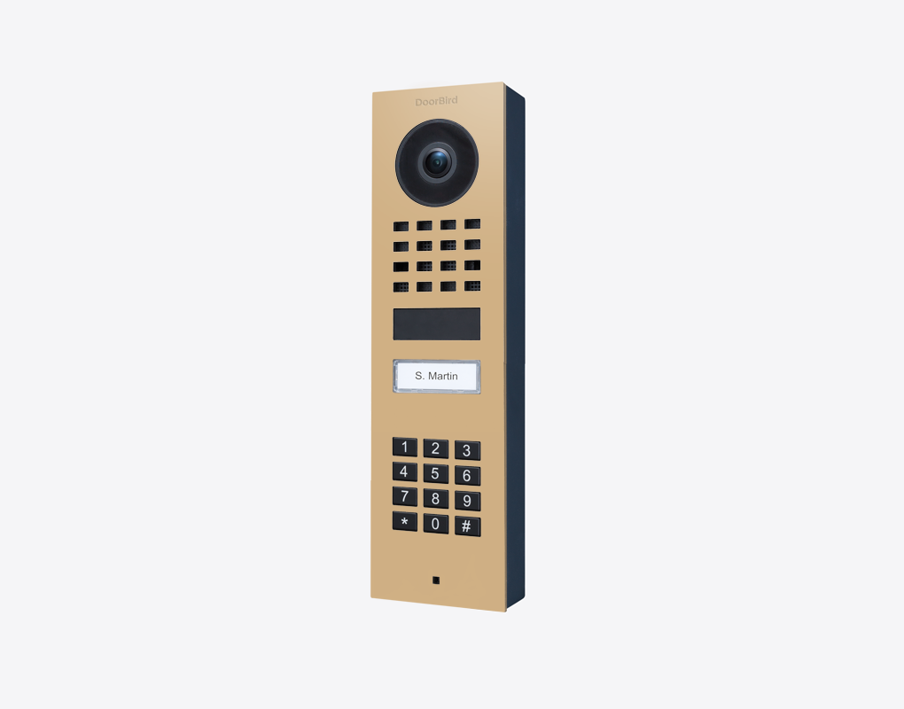 DoorBird surface-mount video door station in beige with camera lens and keypad call button