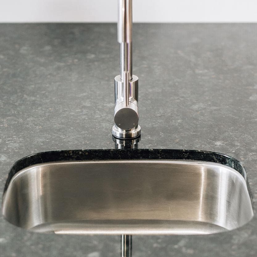 Stainless steel undermount sink front edge with integrated faucet base