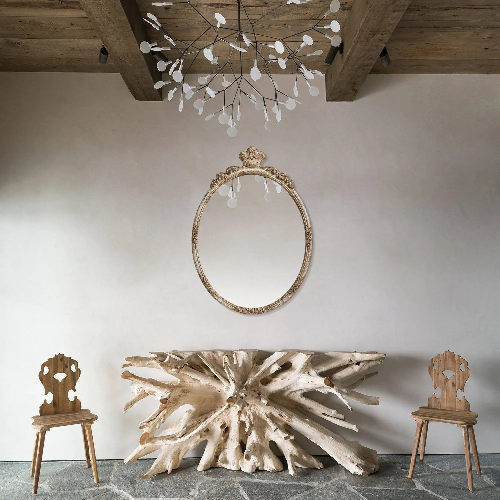 Oval wall mirror with distressed wood frame and carved detailing, rustic decor look.