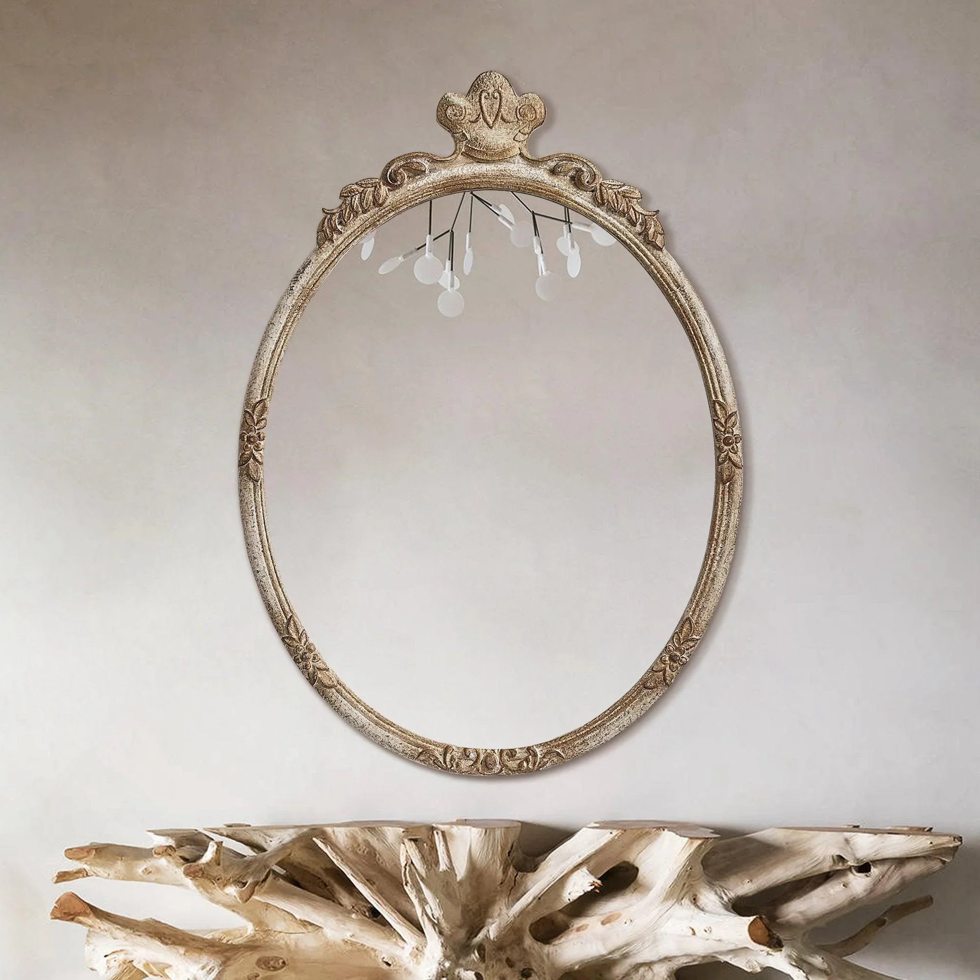Oval wall mirror with distressed wood frame and ornate top crest, rustic style.