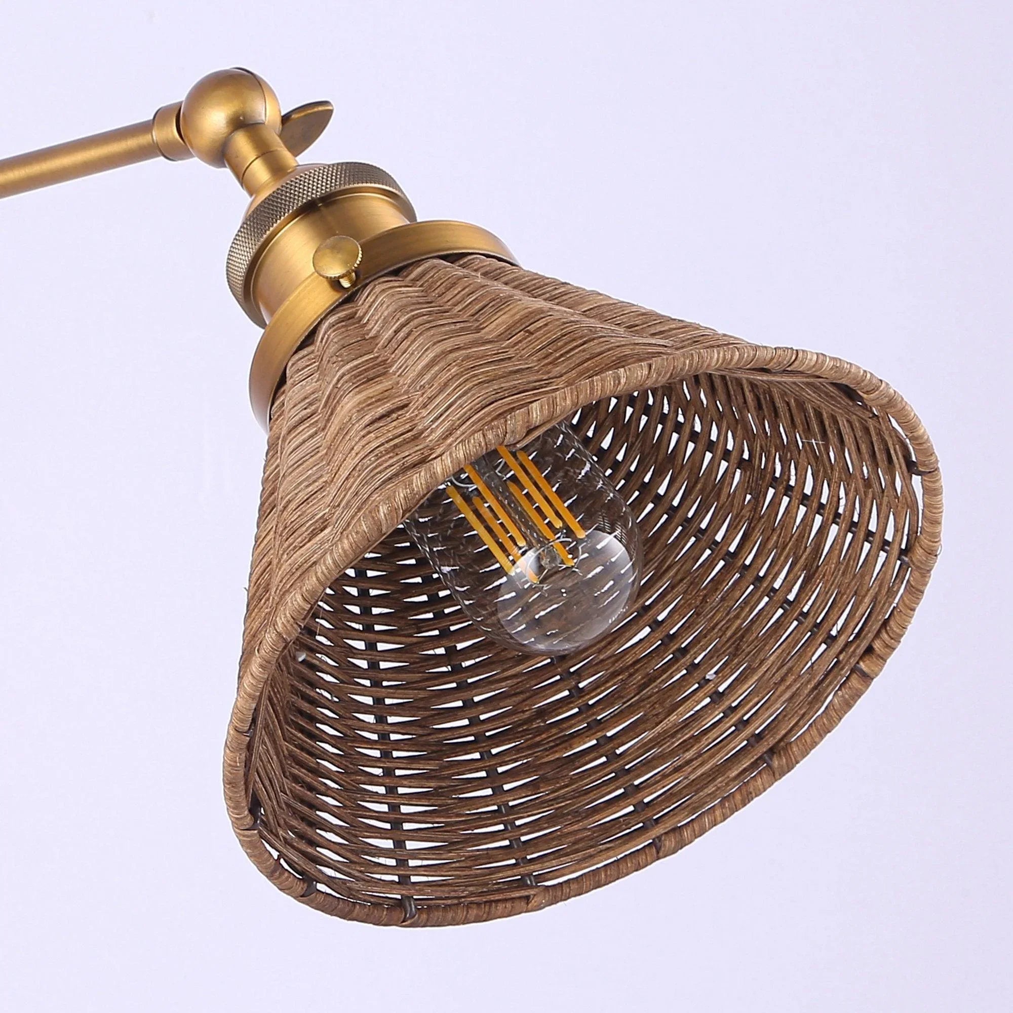 Close view of golden wall sconce arm and rattan shade with clear bulb centered inside
