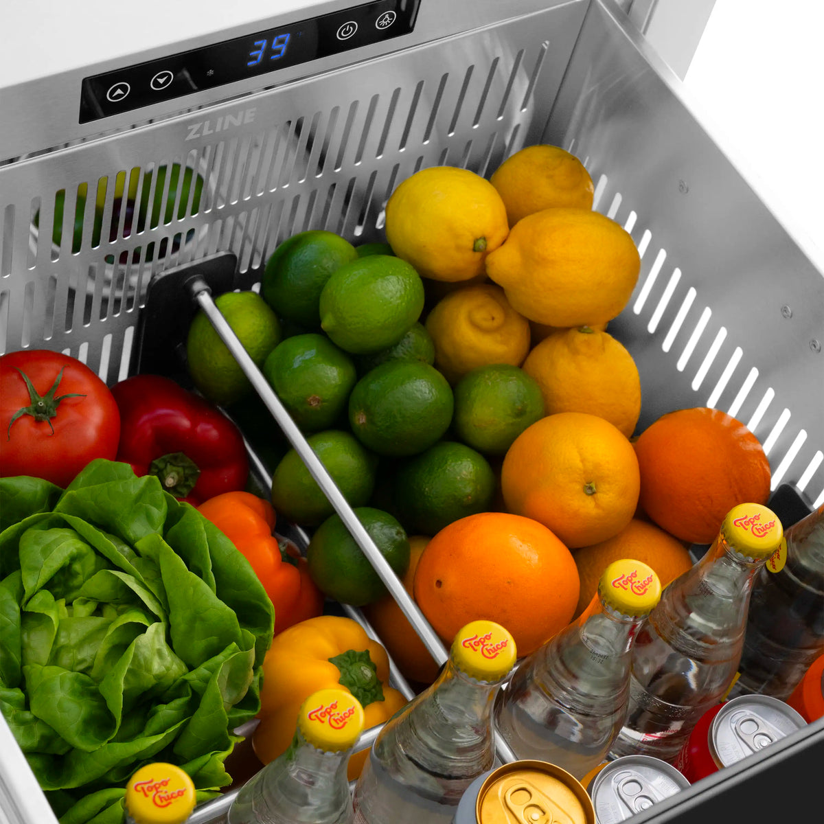 Refrigerator drawer interior with citrus and greens; bottles on lower shelf