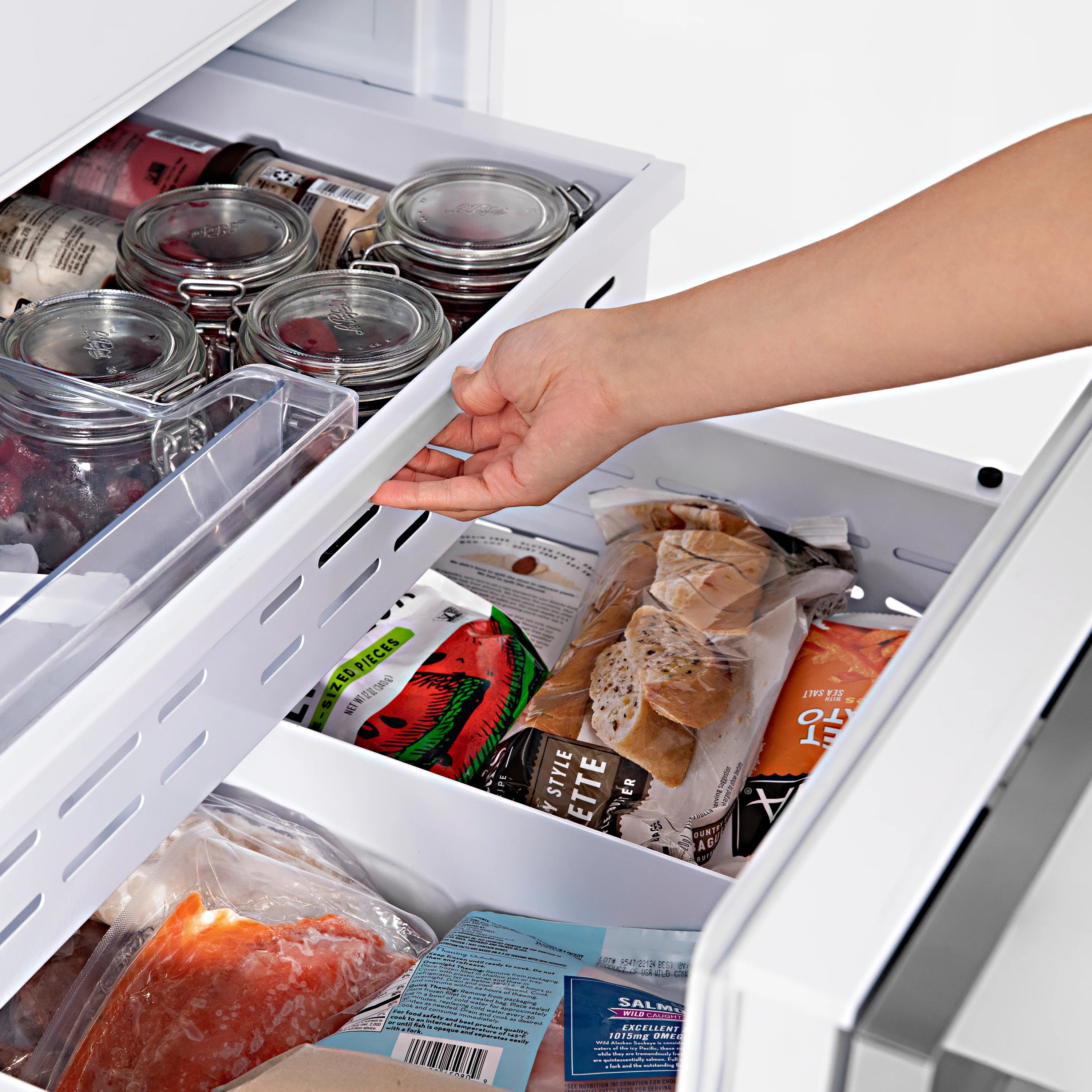 Bottom freezer drawer open with food items and containers inside