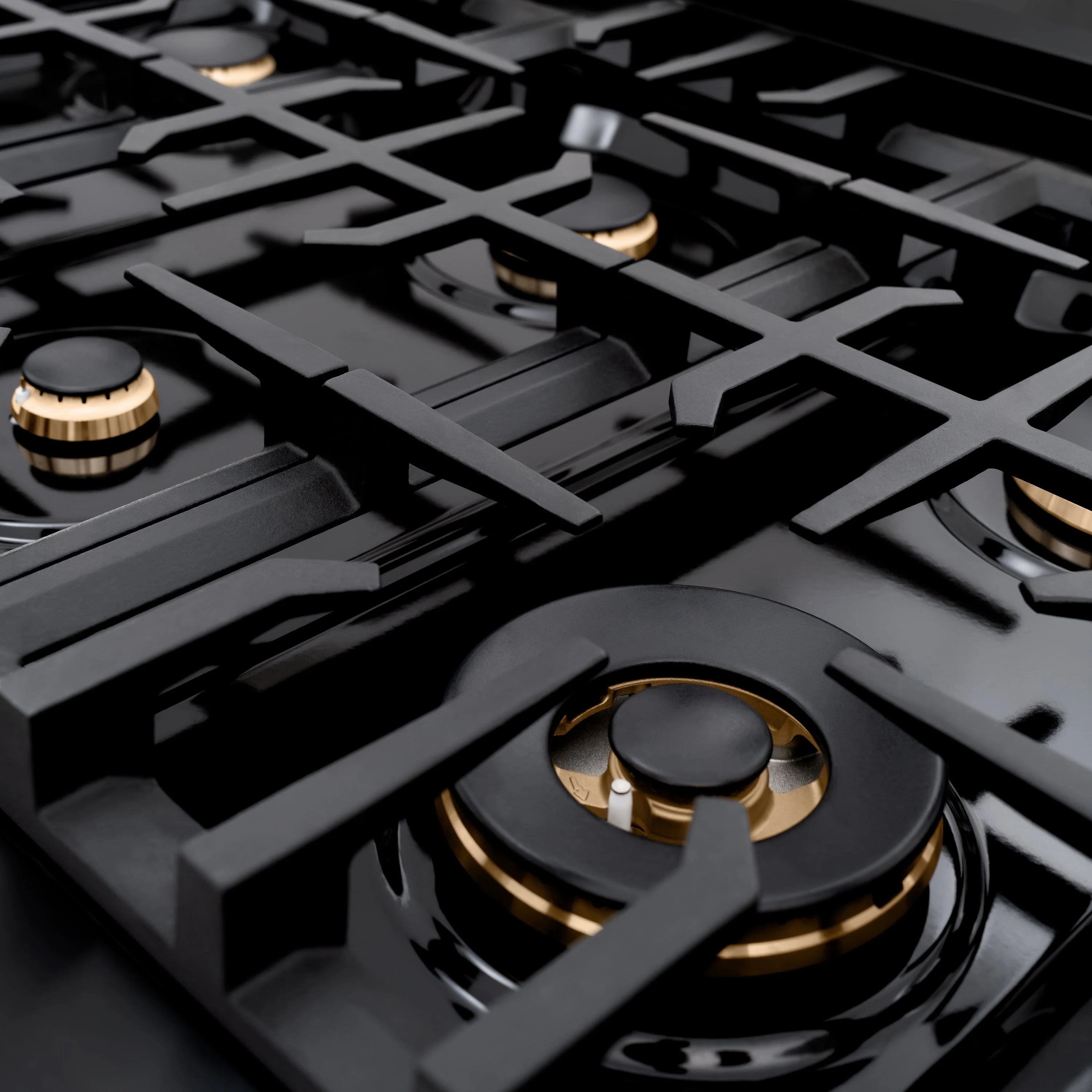 Black gas burner with champagne bronze trim on a glossy black cooktop surface