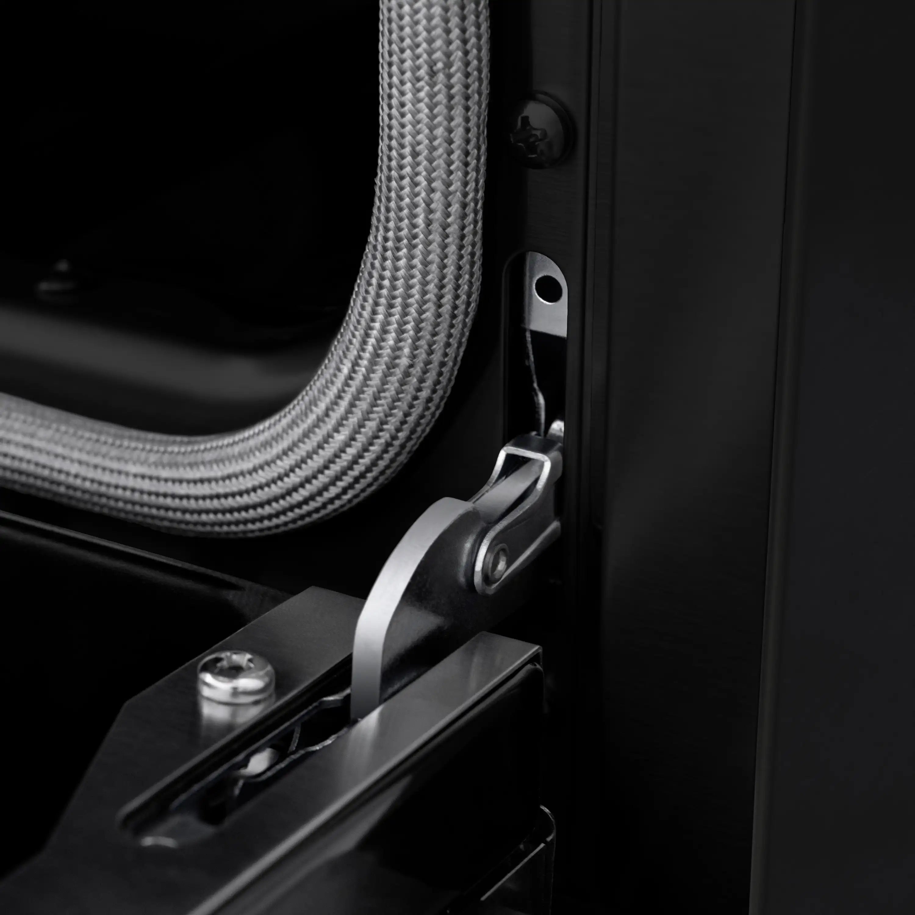 Close-up of black oven door hardware and a braided metal hose