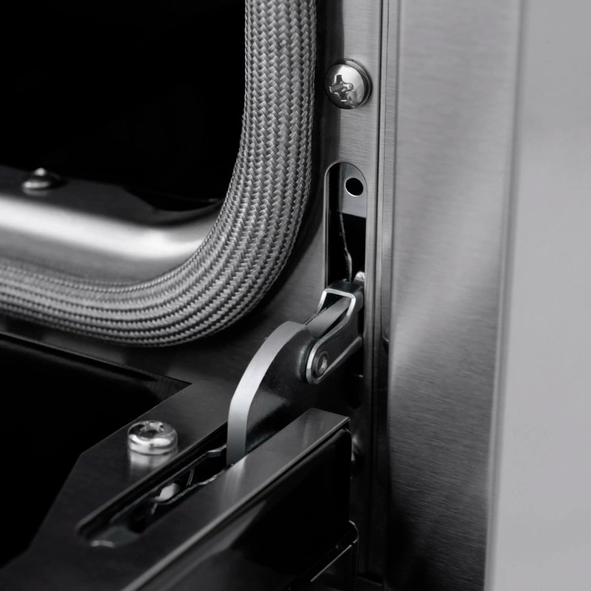 Side detail of stainless gas range with braided gas line connection and metal latch