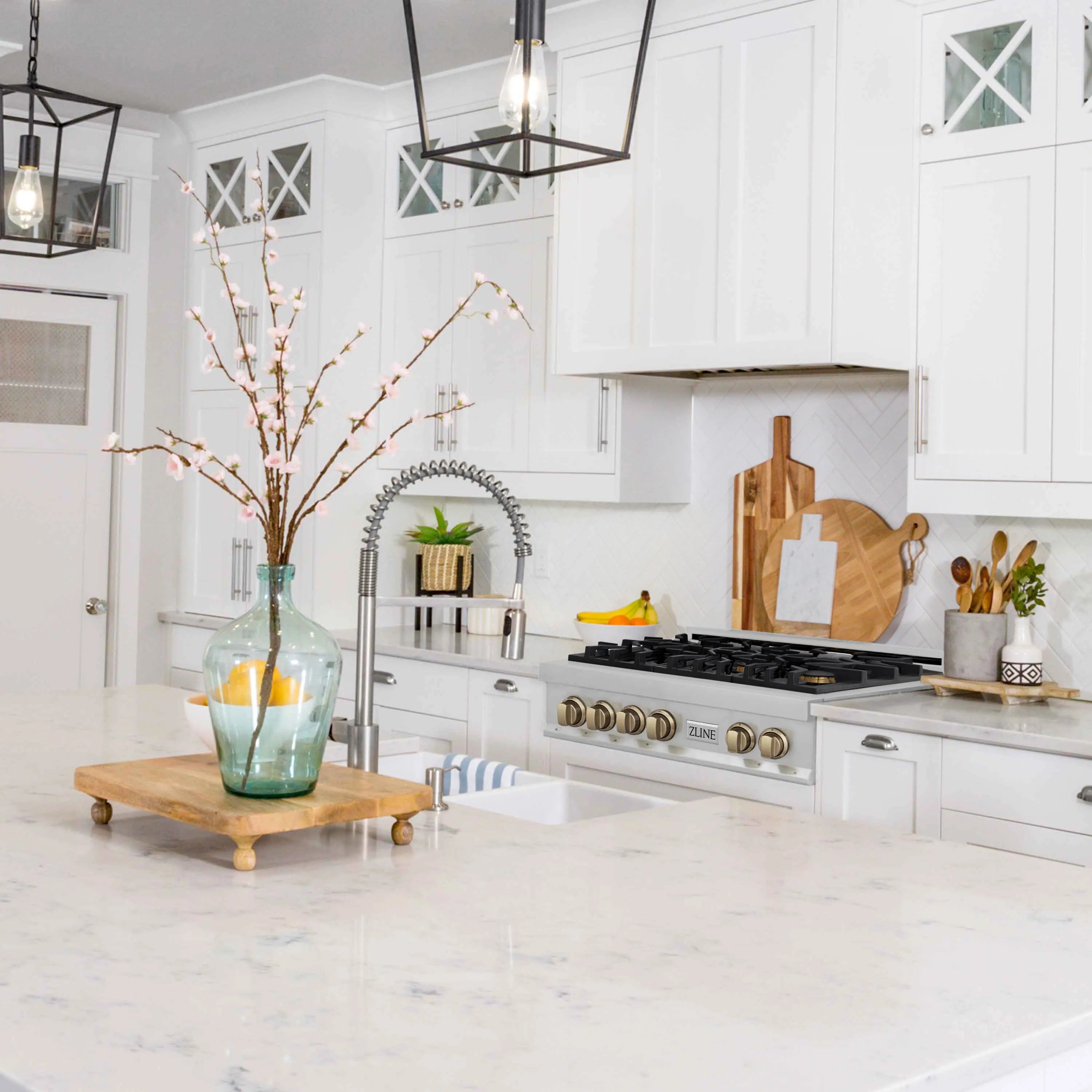 Stainless six-burner gas rangetop with champagne bronze knobs in a white kitchen