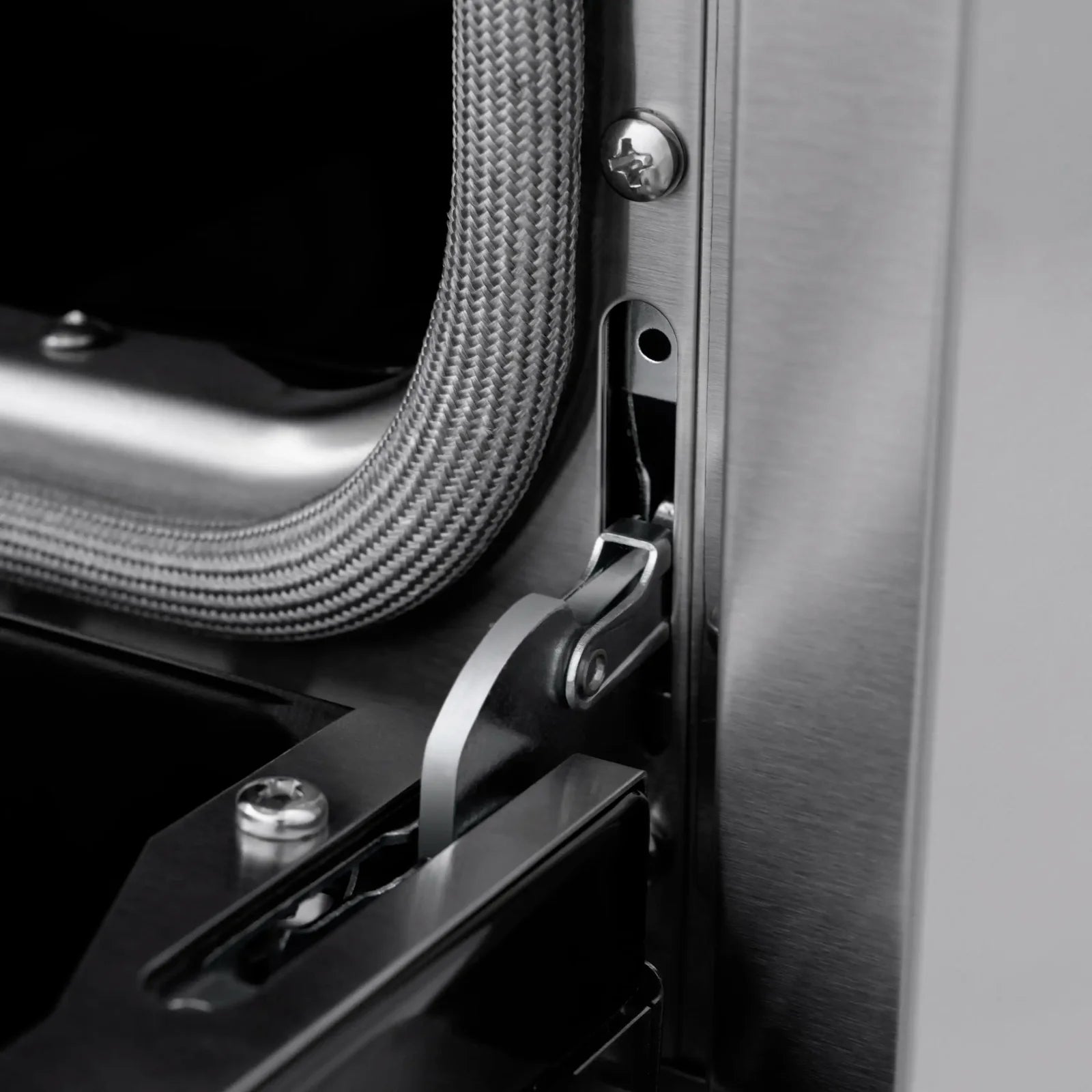 Stainless dishwasher door hardware with gray hose connection and latch detail